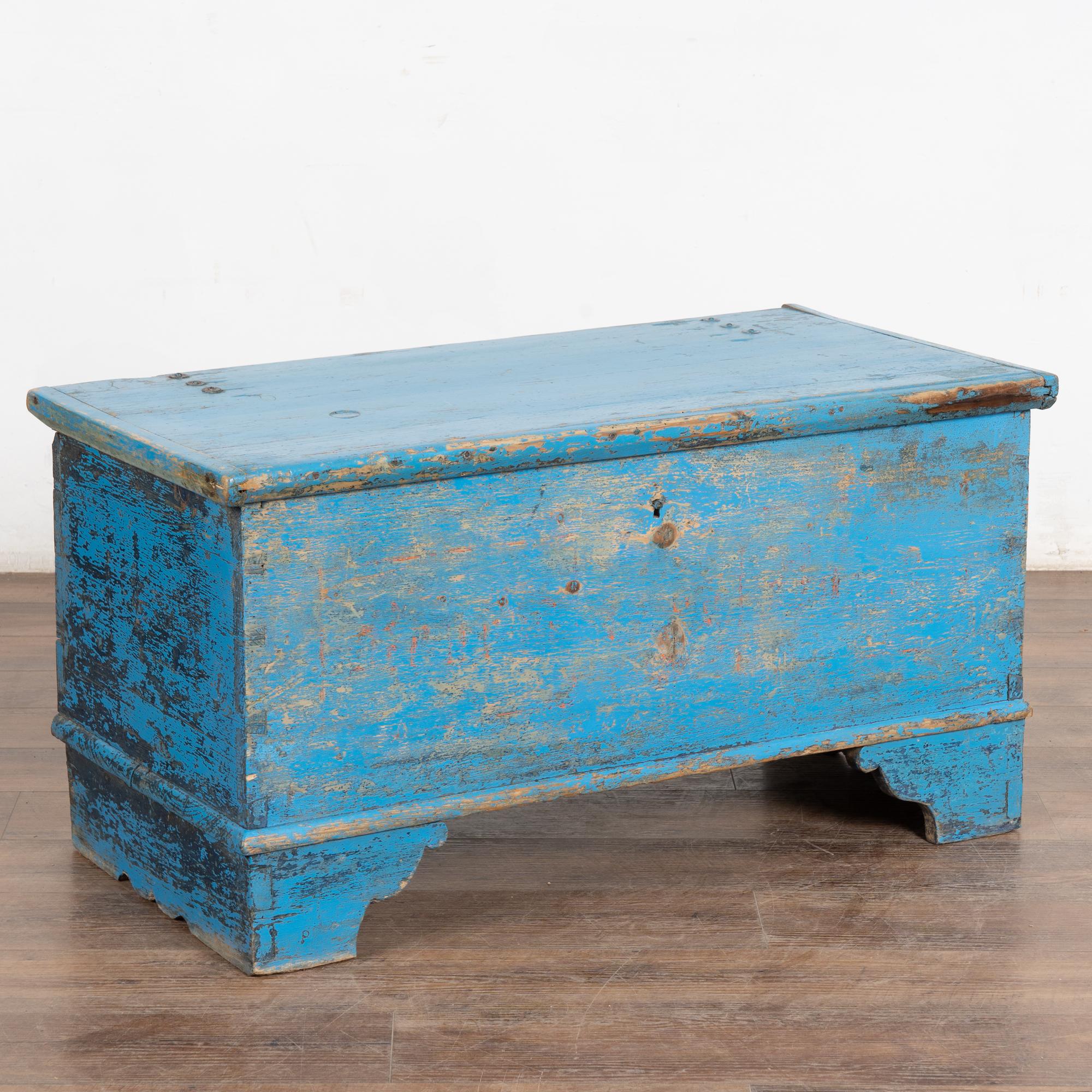 This delightful trunk still has the original blue painted finish, which has been distressed through the passage of years and use revealing much of the original pine below. 
See the exposed dovetail joints and interior upper box with lid to hold
