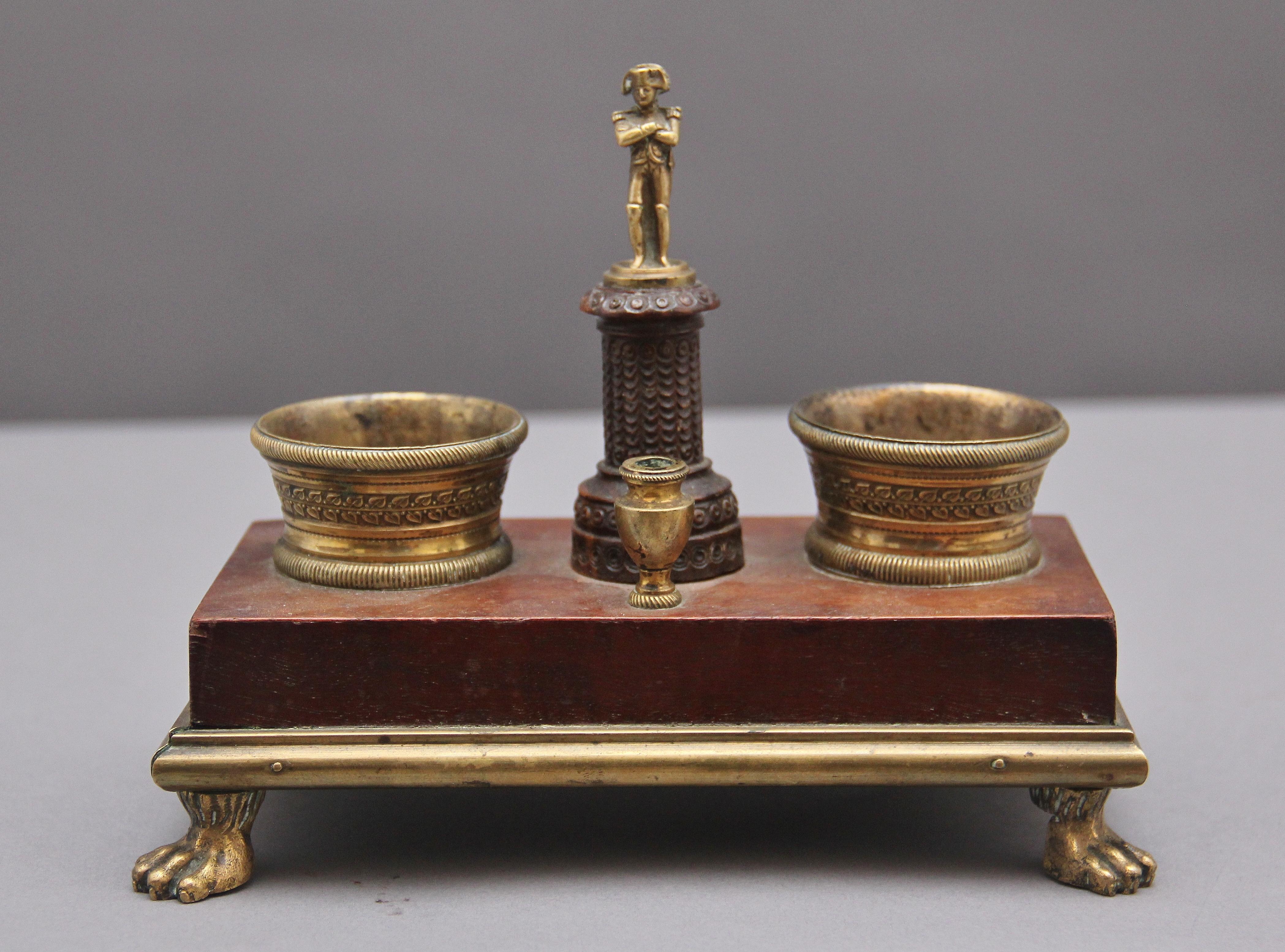 Graziosa scrivania francese del XIX secolo in mogano e ormolu, con piedi a zampa d'asino in ormolu, due calamai e un portapenne, al centro una colonna in legno intagliato con Napoleone. 1820 circa.
 