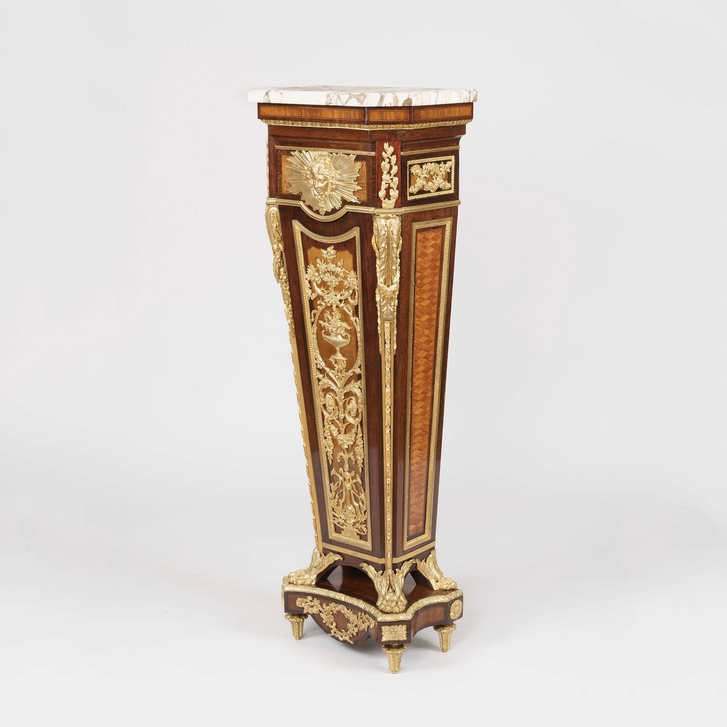 A Pedestal by E. Kahn of Paris
 After a model by Jean-Henri Riesener

Constructed in the Neo-Classical manner in fine specimen woods and high quality ormolu work; the incurved base, rising from ormolu toupie feet and conforming claspwork, the