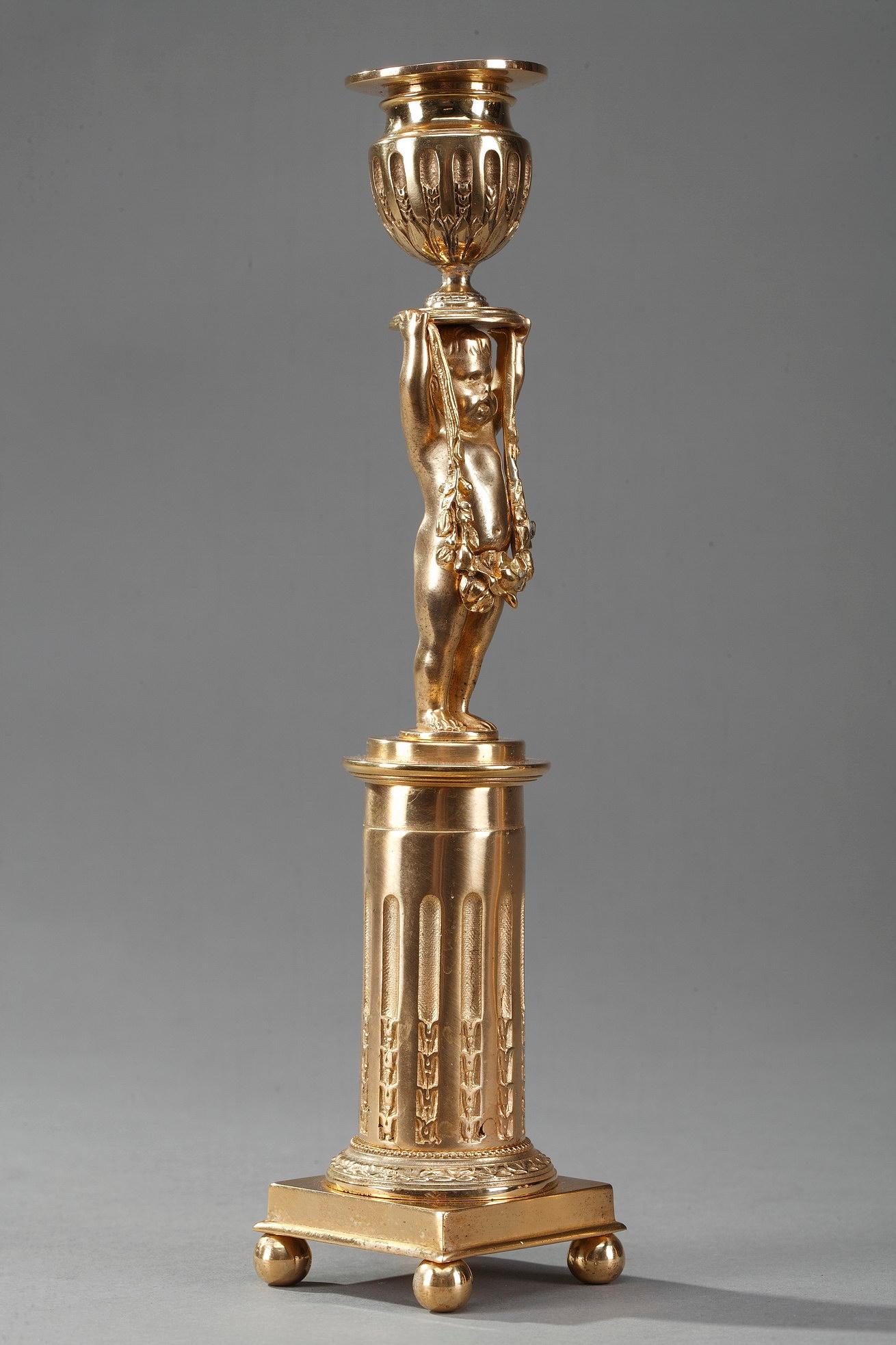 Ein Paar antike Kerzenhalter aus schönem Ormolu oder vergoldeter Bronze. Sie zeigen die Figur eines Kindes, das auf einem gerippten Zylinder steht und eine Girlande hält, die diskret seinen Mittelteil bedeckt. Er balanciert den Sockel der Kerze auf
