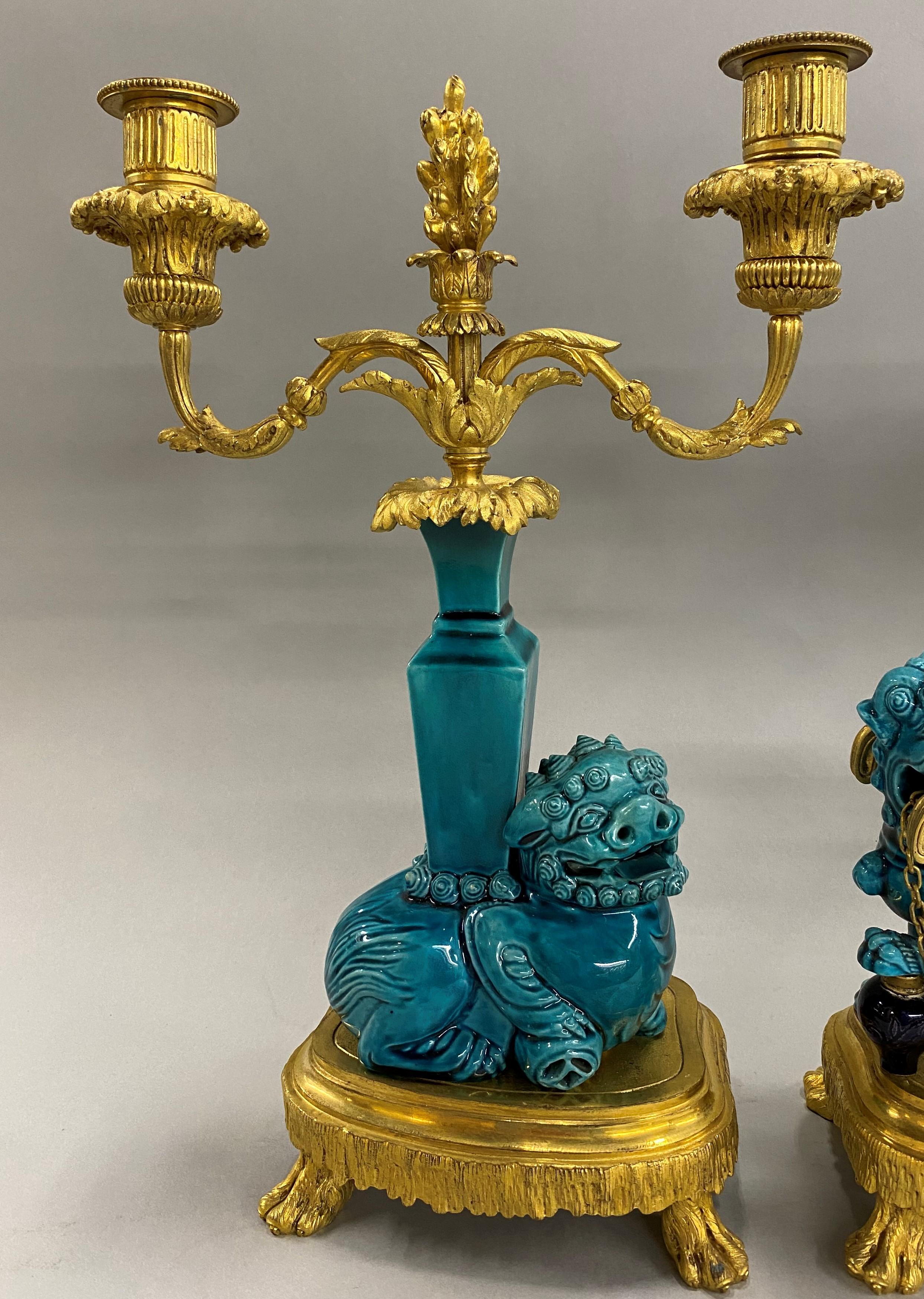 A beautiful ormolu French three-piece porcelain clock set in the Chinese taste with a turquoise glaze, with a pair of two light candelabra flanking a central urn with clock, each featuring foo dog decoration. The set dates to the 19th century in