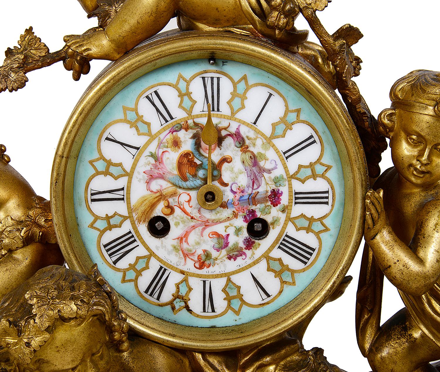 An enchanting 19th century Louis XVI style gilded Bacchus influenced ormolu mantel (fireplace) clock depicting three putti rolling a barrel on the back of a cloven hoofed putti. The hand painted porcelain clock face within the barrel has an eight