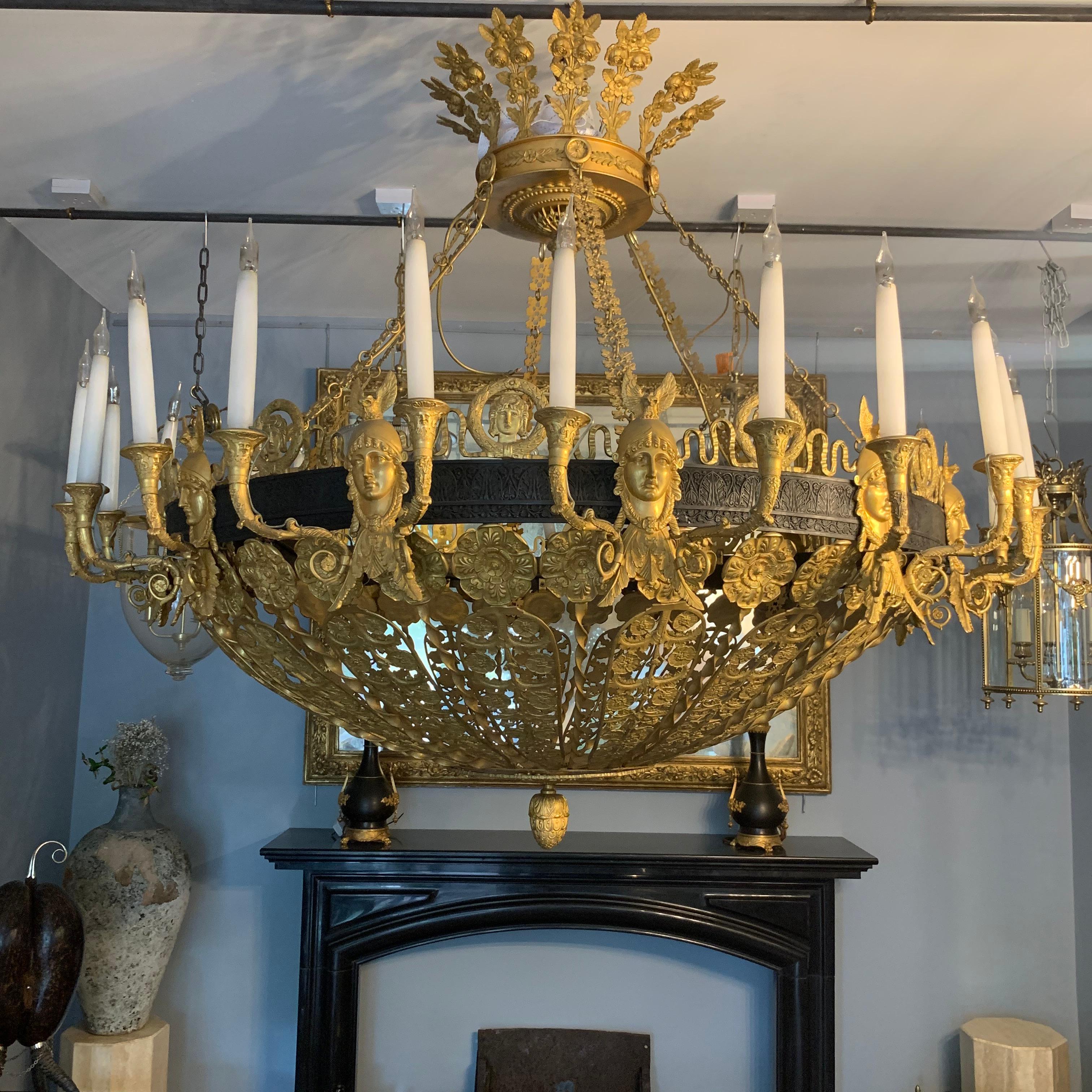 Ormolu and Patinated Bronze Twenty four light Chandelier of pierced dished form, 19th Century, the crown form corona over foliate cast linked chains, suspending a circular pierced dish cast with classical masks and foliate panels.

This light was
