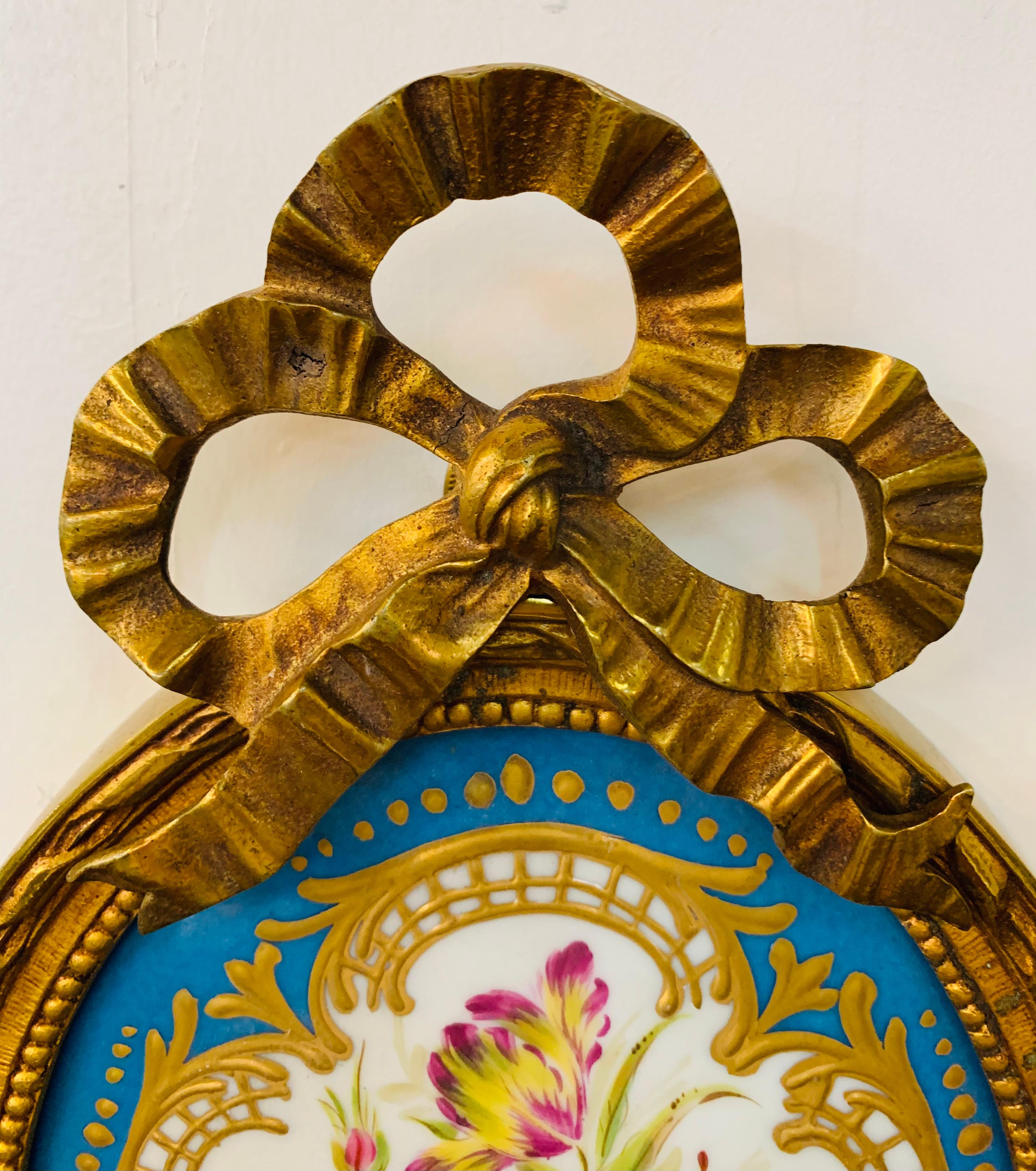 An elegant 19th French century ormolu sconce with Limoges hand painted porcelain. The two candelabra lights sconce features a fine oval shaped porcelain with center flowers design in blue, pink, white and gold elegantly framed and topped with a