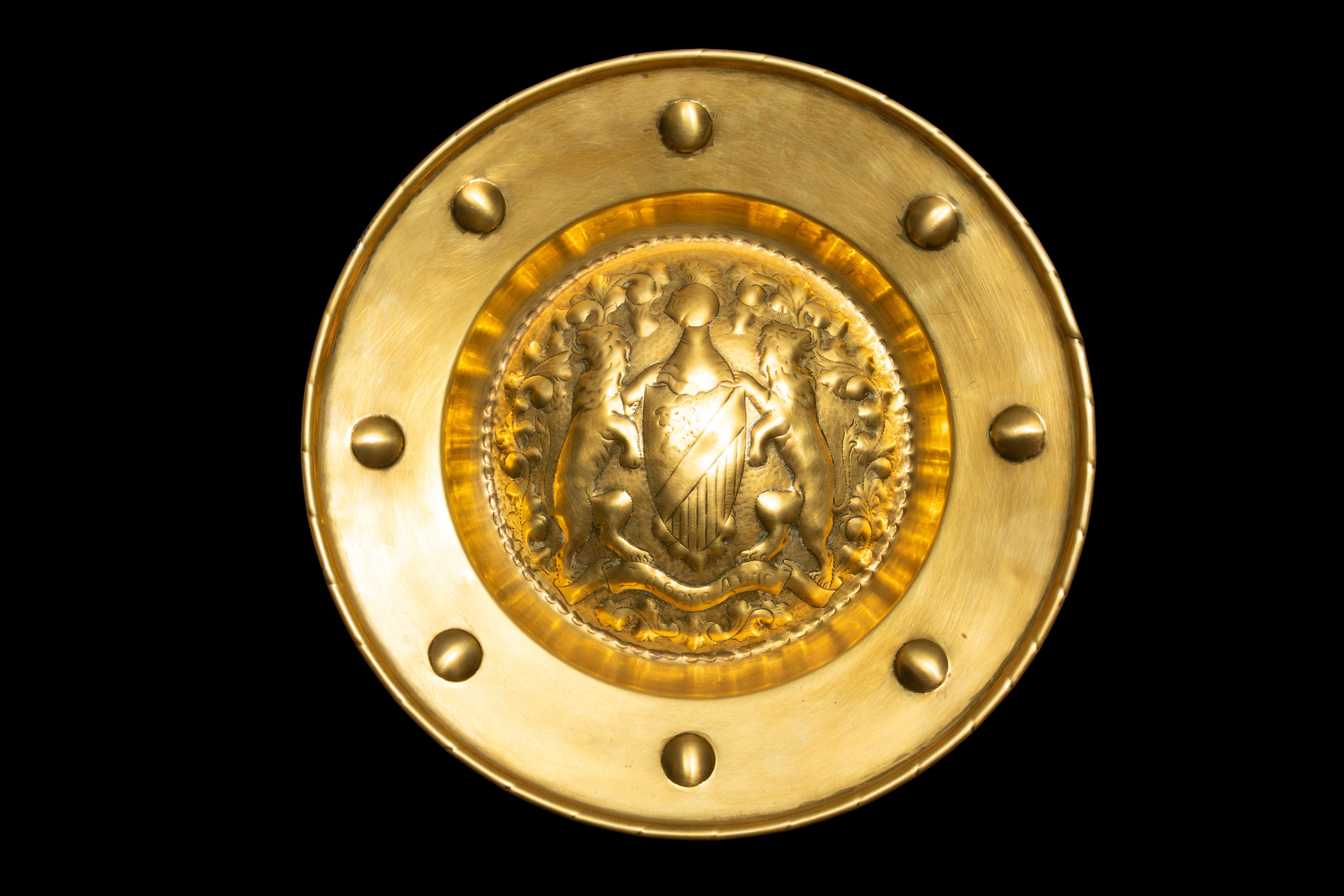 18th Century Ornamental Brass Alms Dish featuring an English coat of arms, measuring approximately 18.25 inches in diameter. This exquisite piece serves as a historic and decorative tray designed for the collection of offerings from congregations.