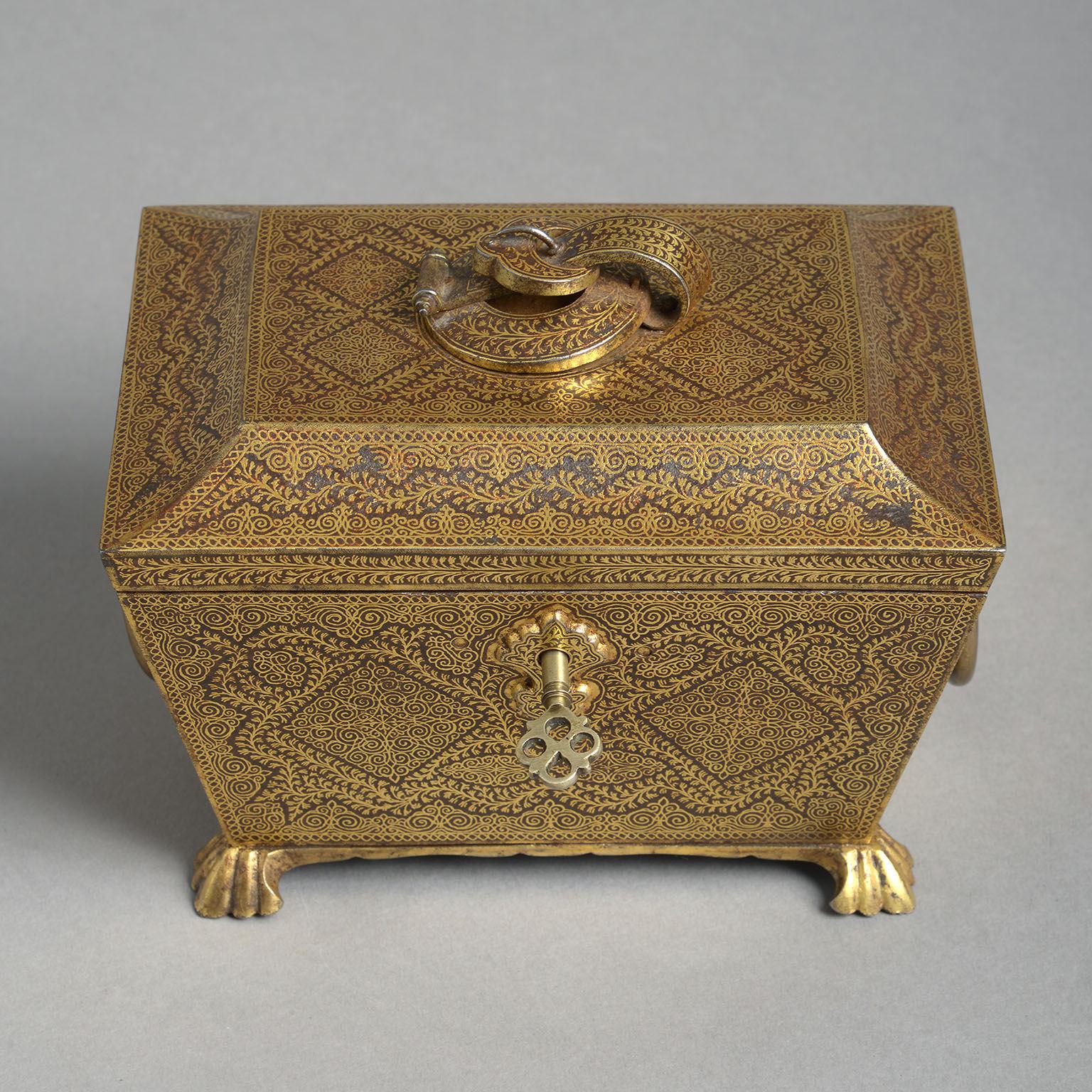 The steel sarcophagus form with fine, all-over Koftgari decoration in yellow gold. The hinged, tented lid with central buckle decoration a above a tapering body with ring handles to the sides and raised on braganza feet. Complete with original key.
