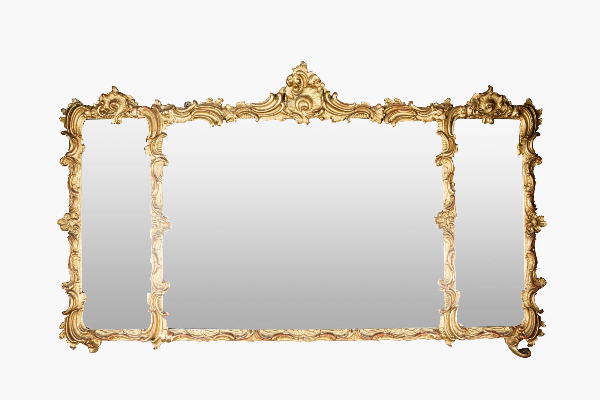 19th century Ornately decorated Regency gilt overmantel mirror with three glass panels. The intricately detailed frame with floral embellishments, and rococo-style flourishes, includes elegant acanthus leaf motifs, shells, and sweeping C-scrolls.
