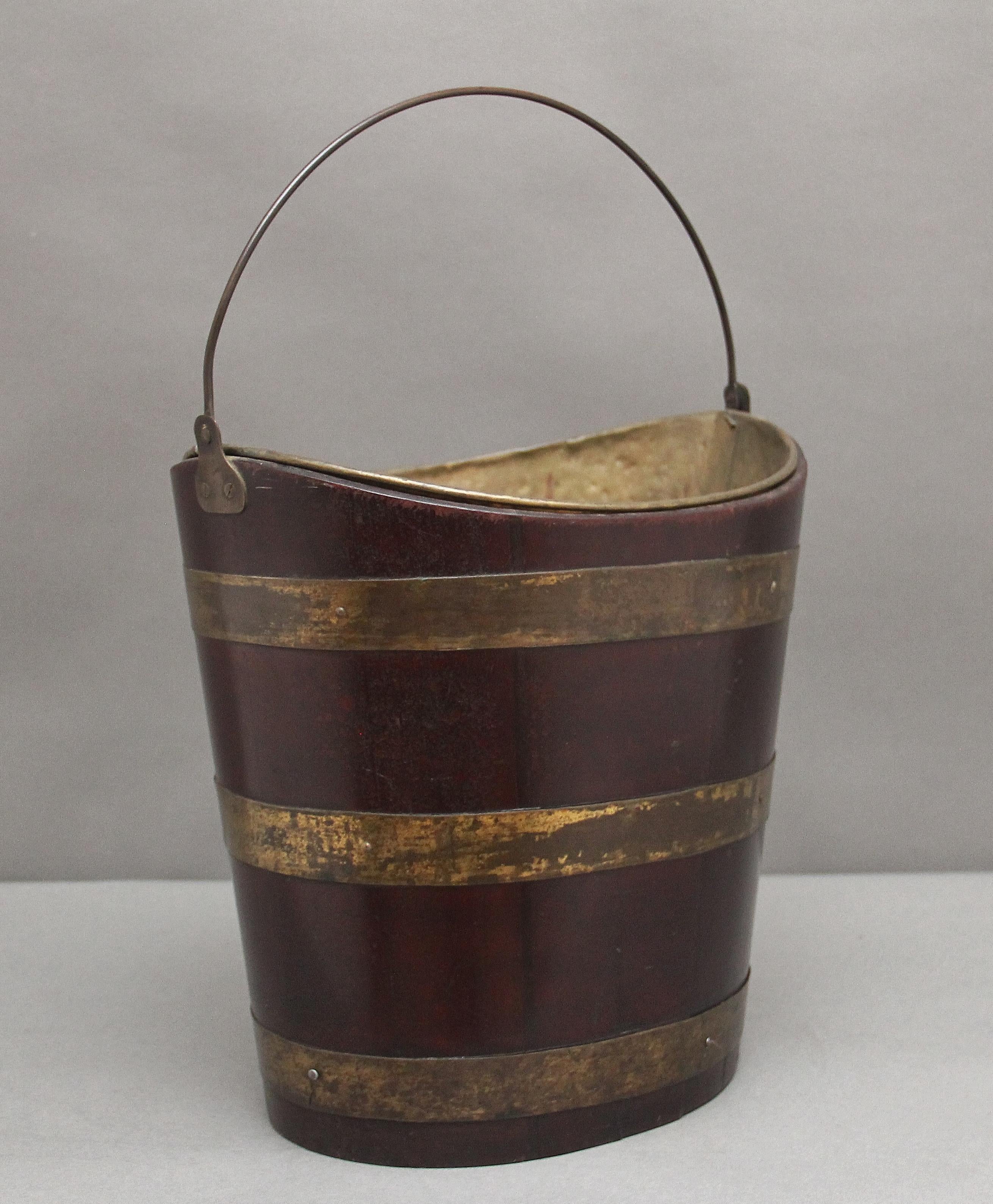 Early 19th Century mahogany oval brass bound bucket with a brass liner and handle.  Circa 1820.