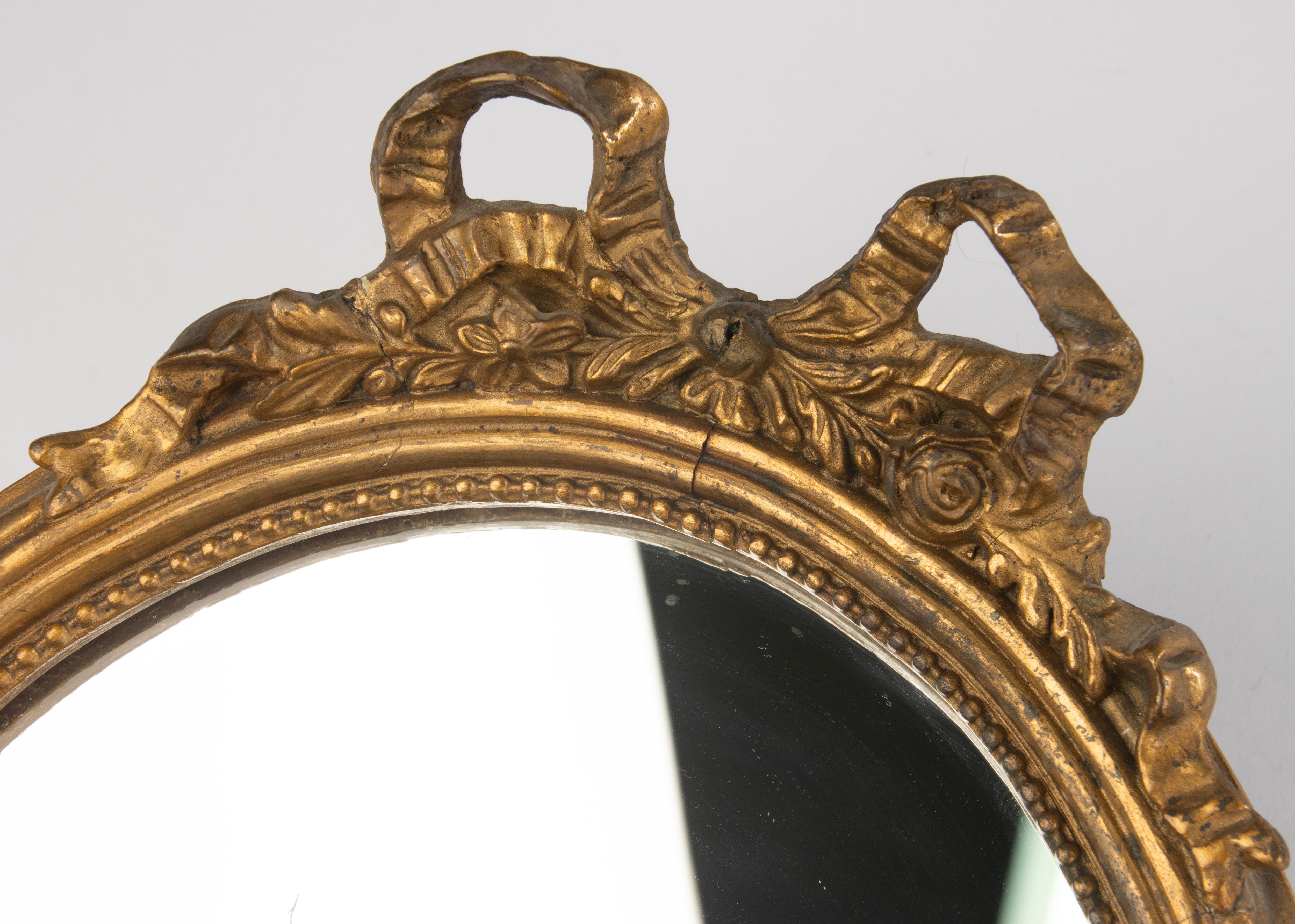 Charming small antique mirror in Louis XVI style, France, circa 1900.
The frame is made of wood with a gesso layer and finished with gold leaf.
Beautifully detailed with delicate beaded edges, ribbon, and floral motifs.
The original glass shows