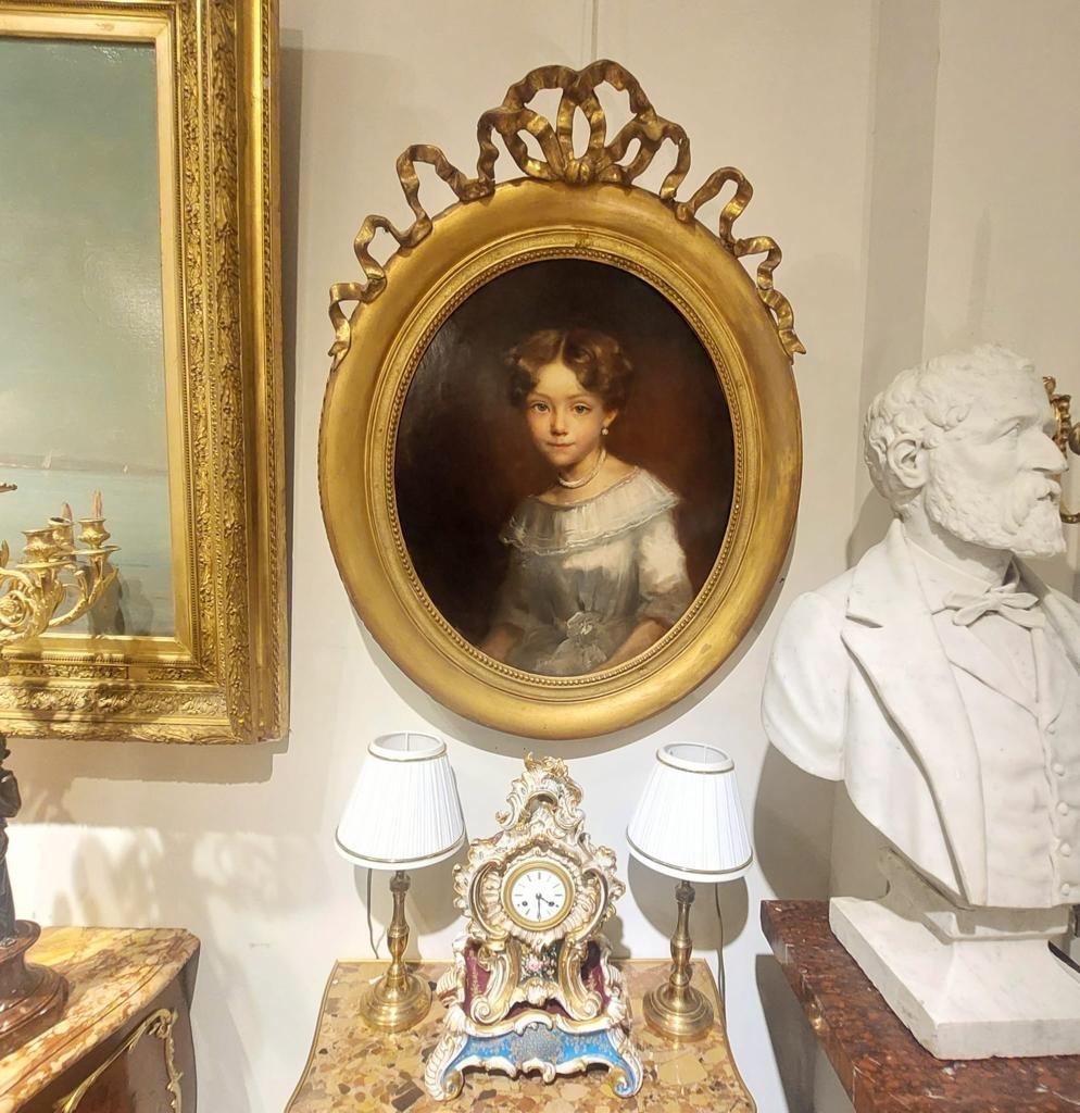 Nous vous présentons cette peinture à l'huile sur toile dans le style de Louis Philippe du 19ème siècle. Elle représente une jeune fille issue d'une famille distinguée, vêtue d'une robe de soie et portant un collier élégant. Son attitude respire la