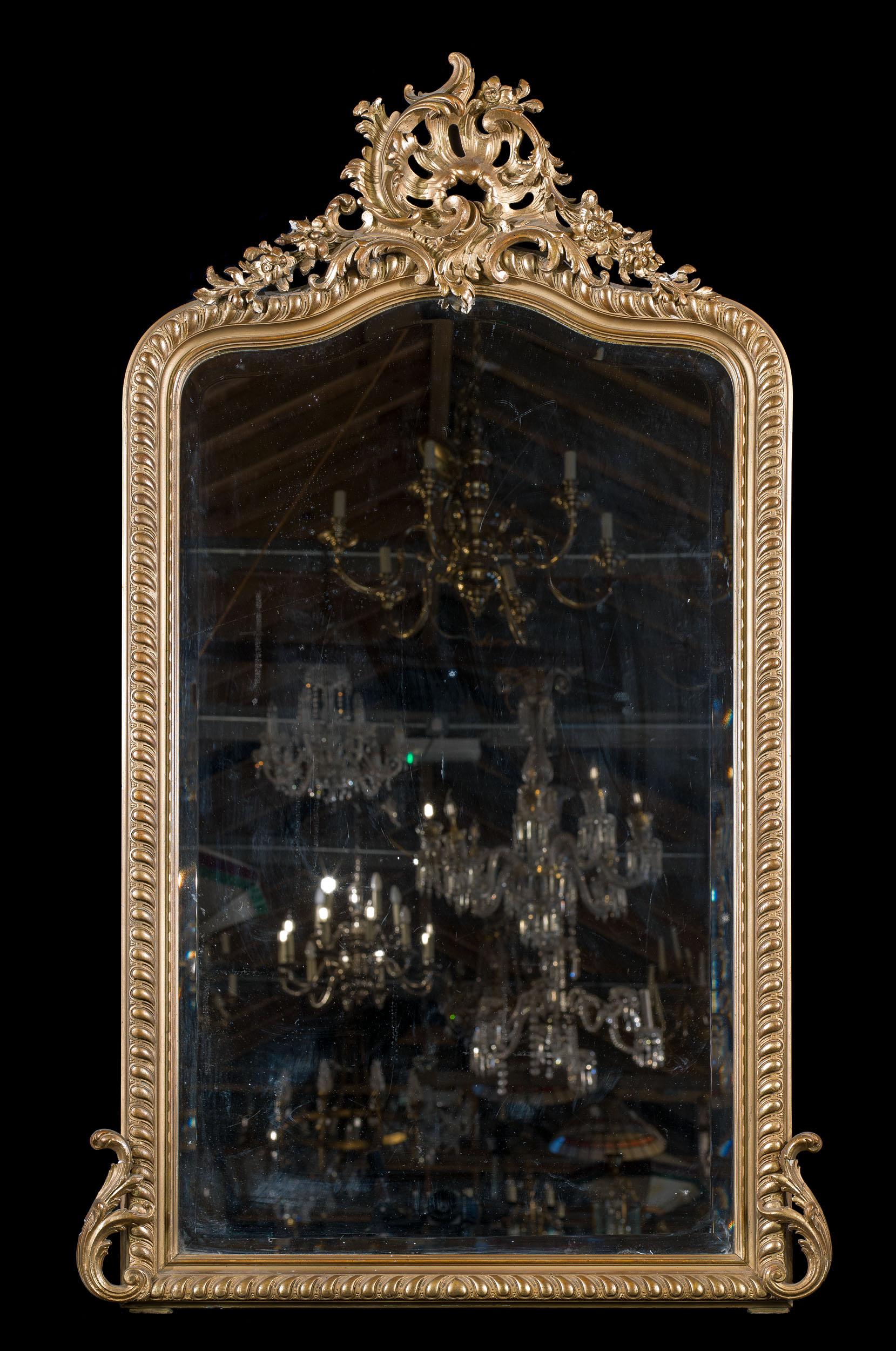 A 19th century Rococo gilt gesso overmantel mirror, surmounted by shell set within foliate c scrolls and trailing flowers. The original bevelled mirror plate sits within a moulded frame.
French, c.1890.