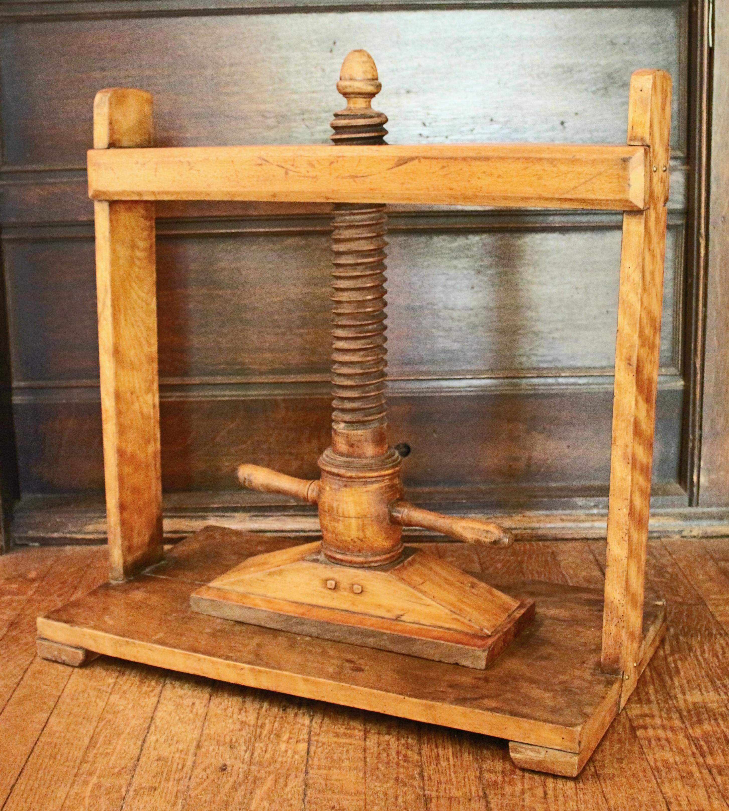 An oversized book press, 19th century, of maple. Probably American, possibly European. Good overall condition, slight warp and split in the base, wear commensurate with age and use. Bracket feet. Acorn finial shaft tip. Measures: 24