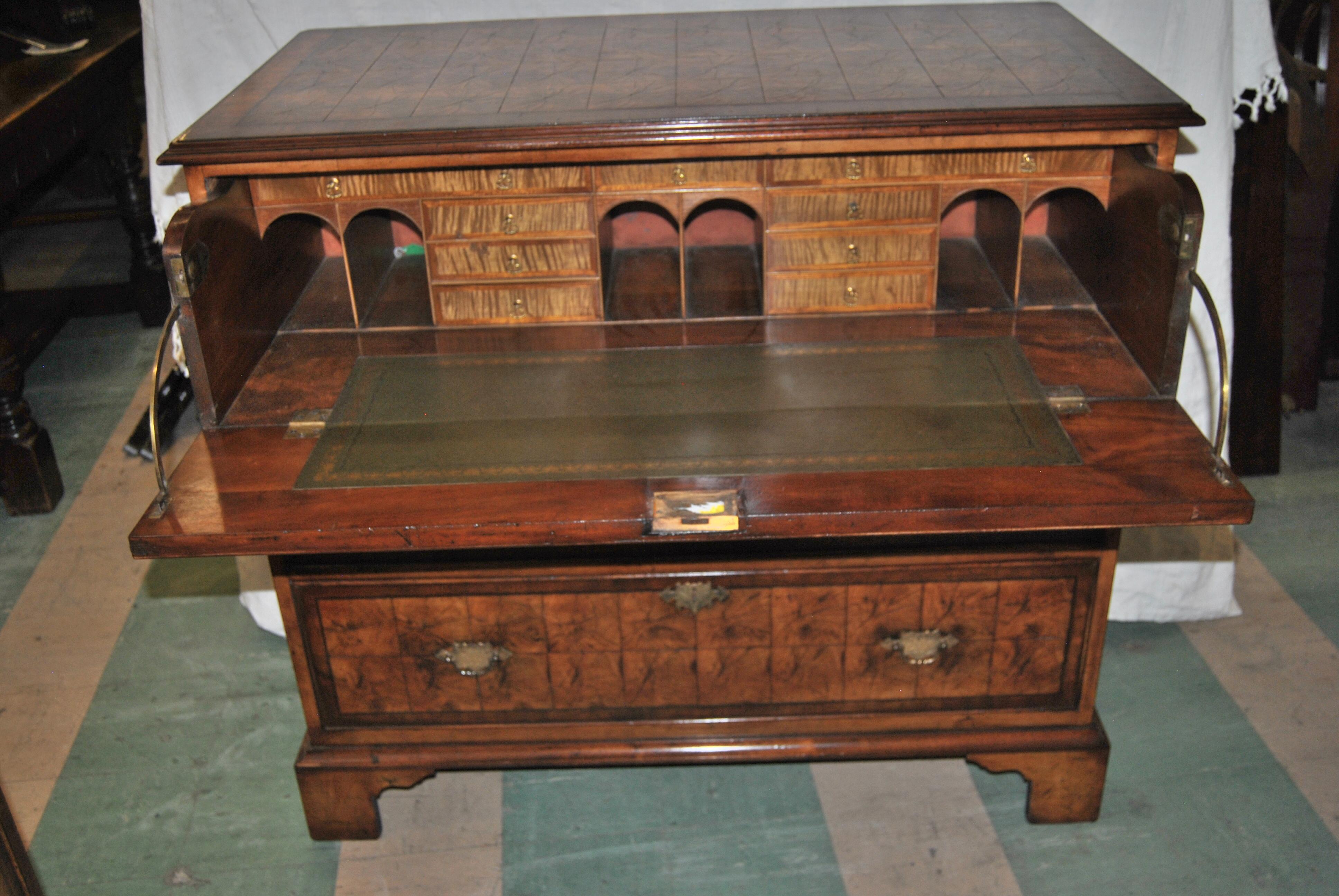 This is a butlers chest or desk made in England, circa 1825. The top has a nicely molded edge and is banded in mahogany followed by a string inlay of ebony with oyster cut walnut to the middle. The top drawer drops down to reveal a desk with 9