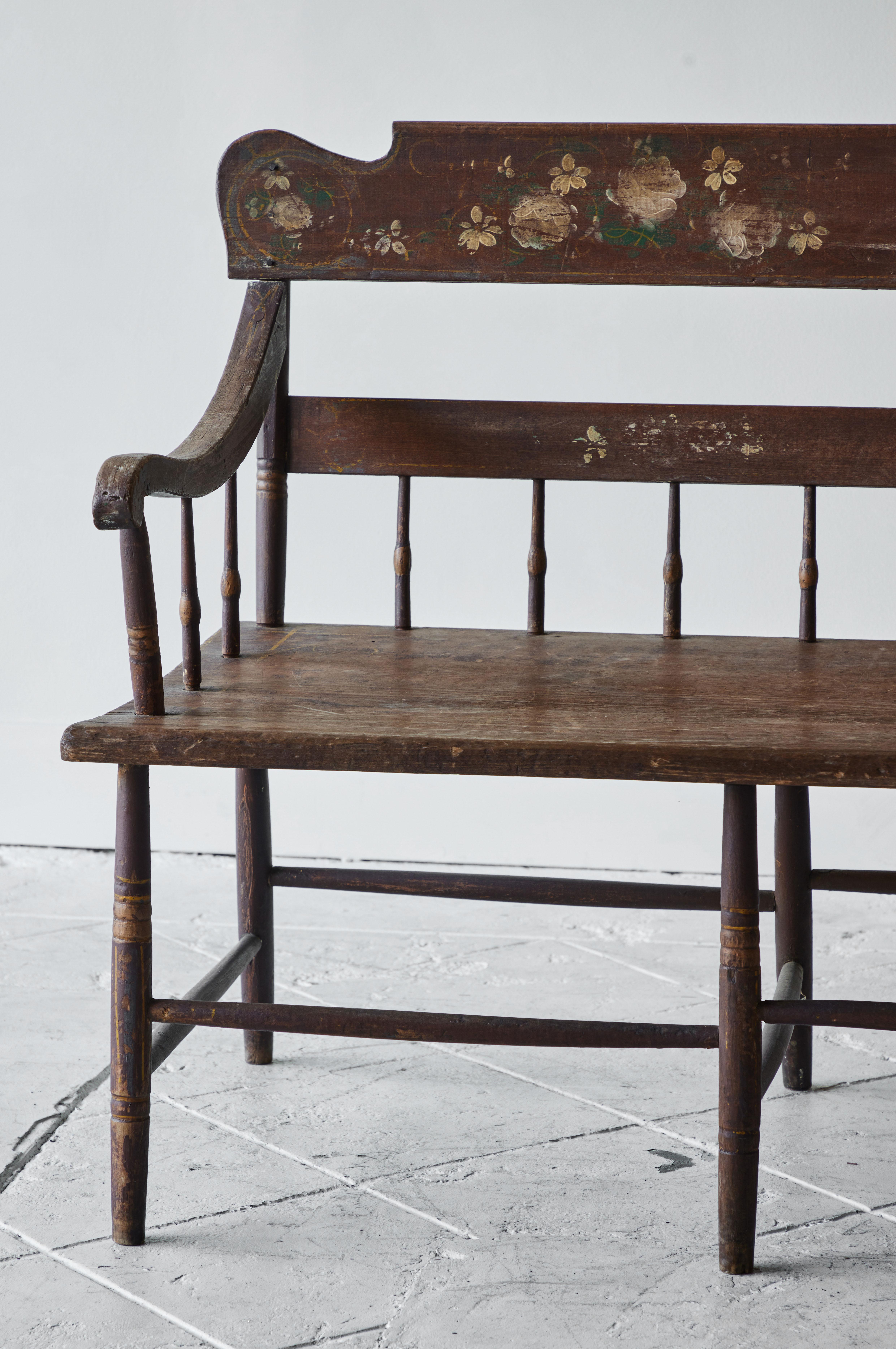 A stunning paint-decorated, Pennsylvania, plank-seat settee from the mid-19th century. This piece features a half-spindle-back style with an intricate crest rail and is curved slightly at the shoulders. This design is typical of rural Pennsylvania