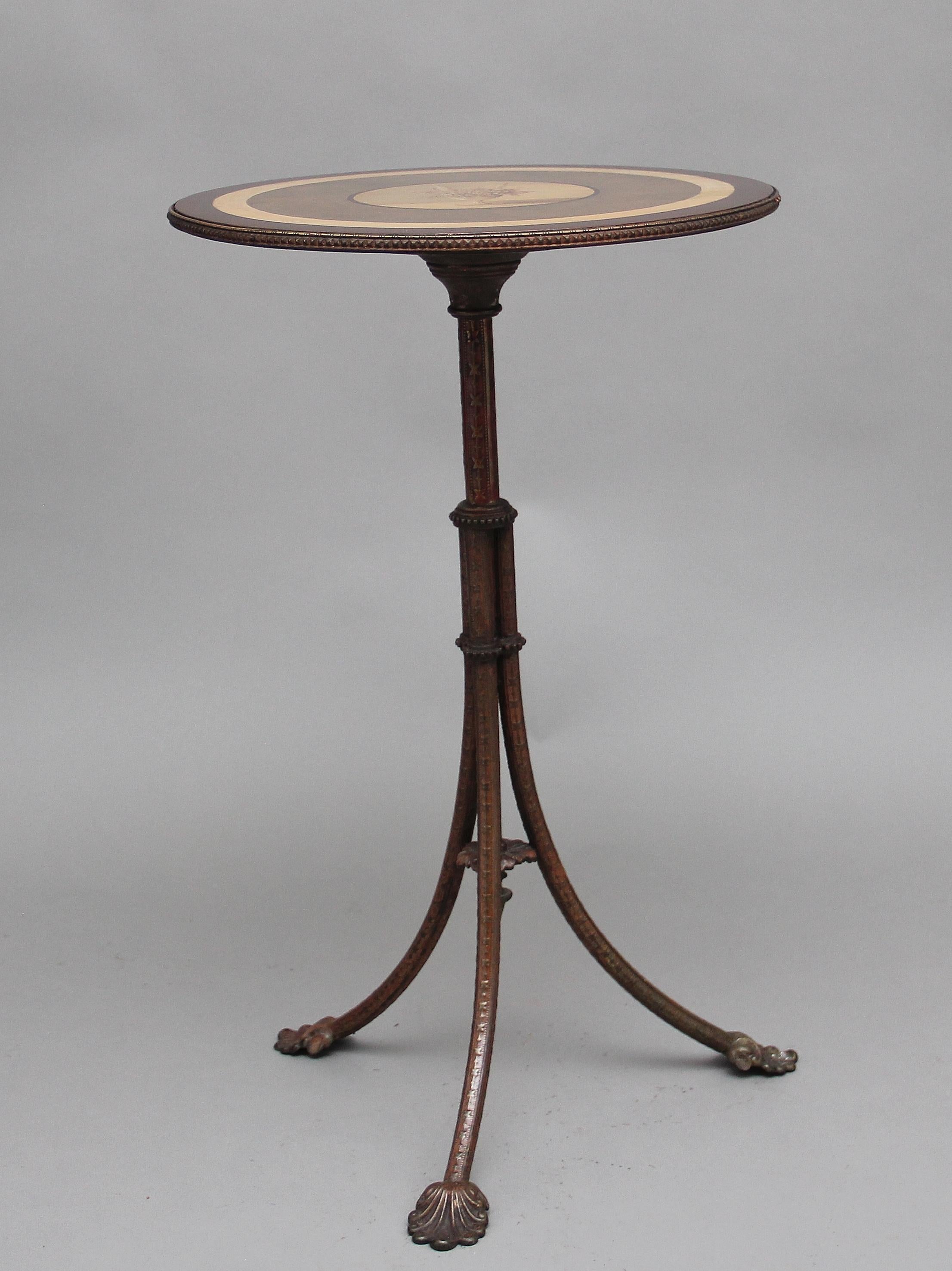 A decorative 19th century occasional table, the painted circular top having various painted boarders and a floral decoration at the centre, the edge of the top having brass decoration, the top supported on a tri form brass base with finely carved