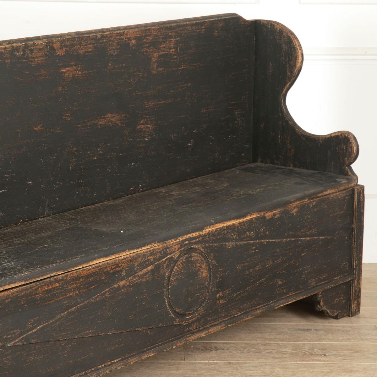 Striking 19th Century Norwegian painted bench, with storage under the seat.

This primitive bench has been painted black, the original coat touched up over the years. The paint has distressed in places, adding to the authentic charm of the piece.