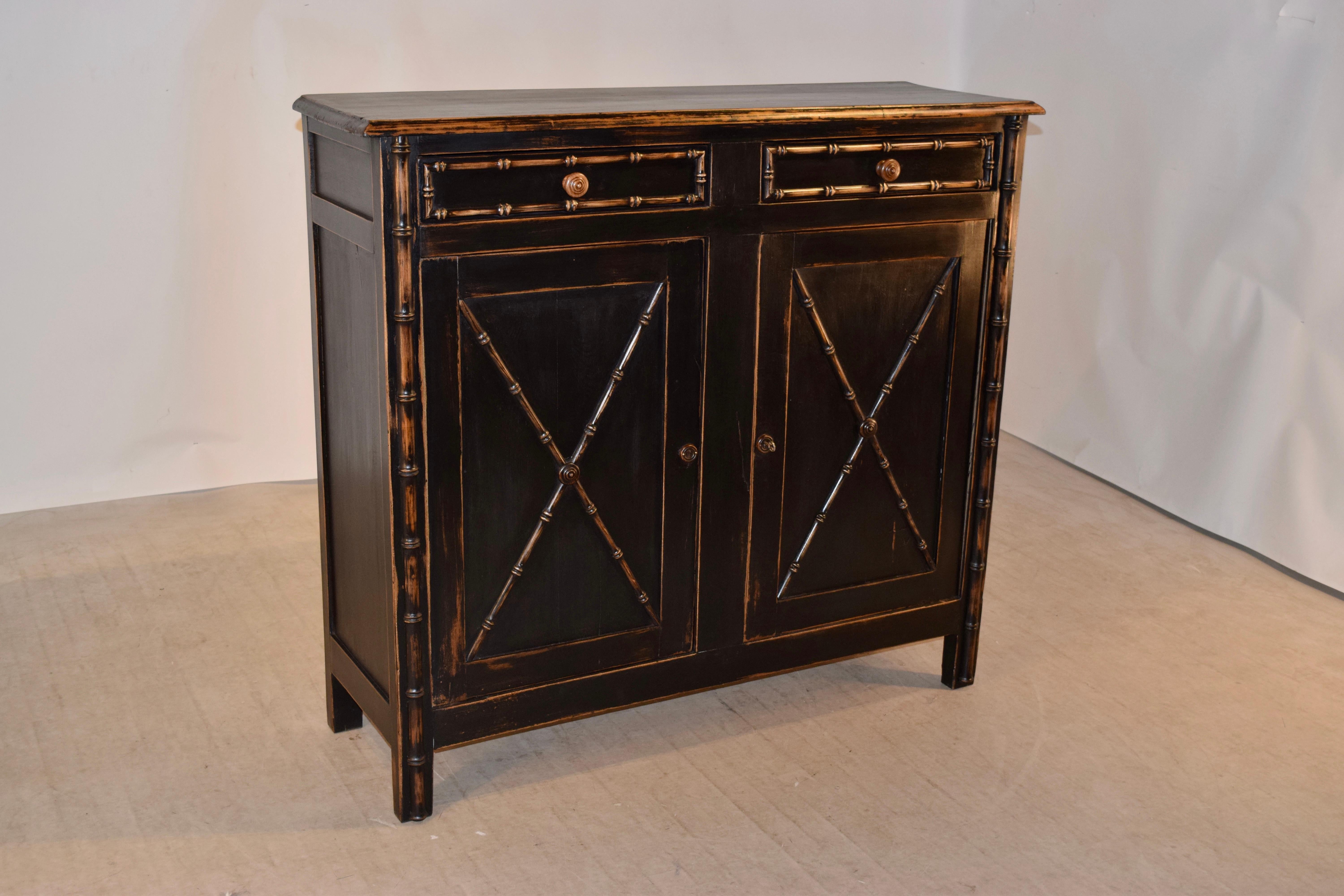 19th century painted buffet from France with a beveled edge around the top, following down to two drawers over two doors, all with faux bamboo molded decoration and flanked with faux bamboo hand-turned applied turnings as well. The sides are simply