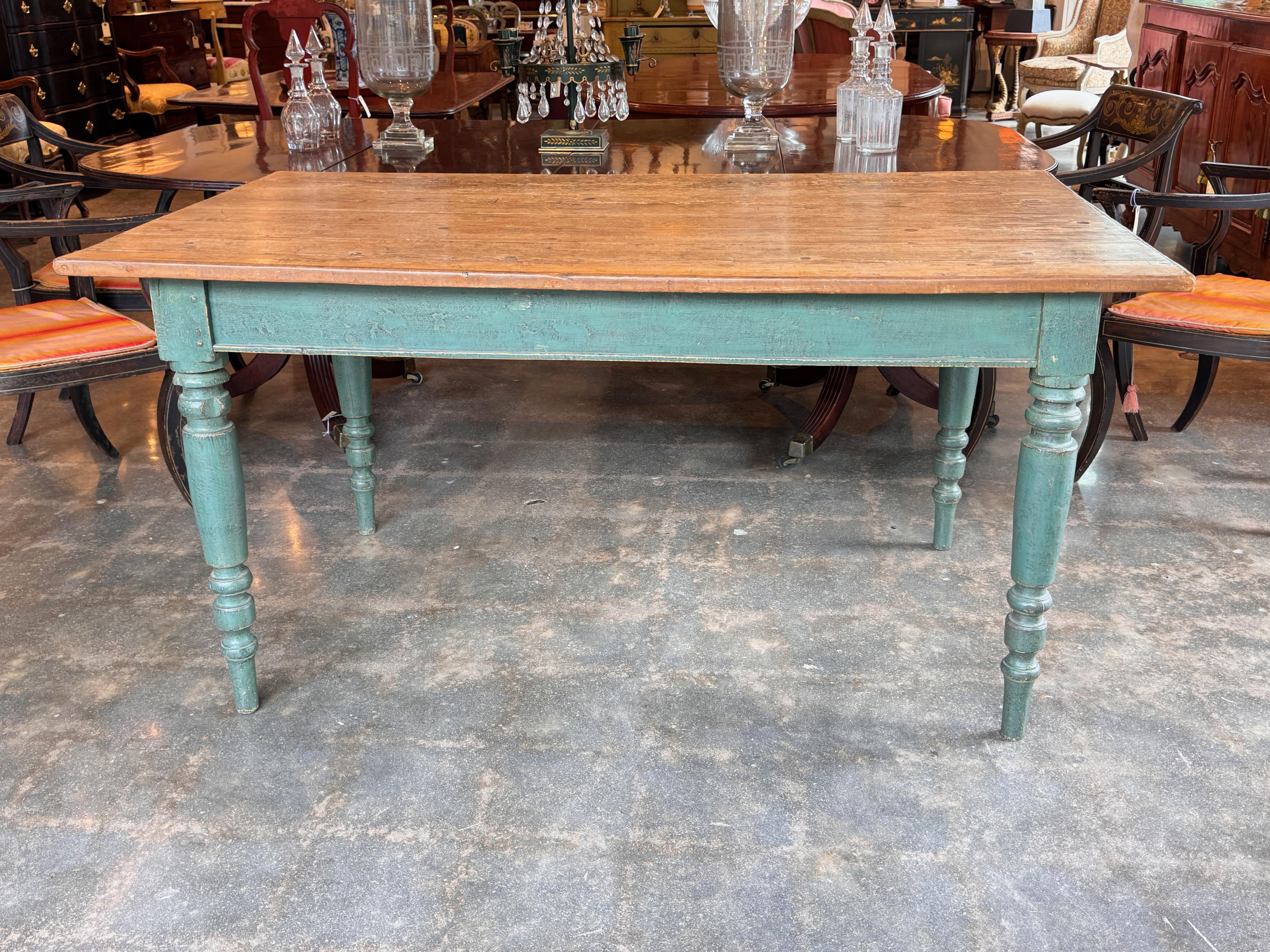 19th century farm table with turned legs and a scrubbed wood top over a painted base. The paint shows age-appropriate wear, revealing a soft patina. Traditional proportions with simple country styling and solid joinery throughout