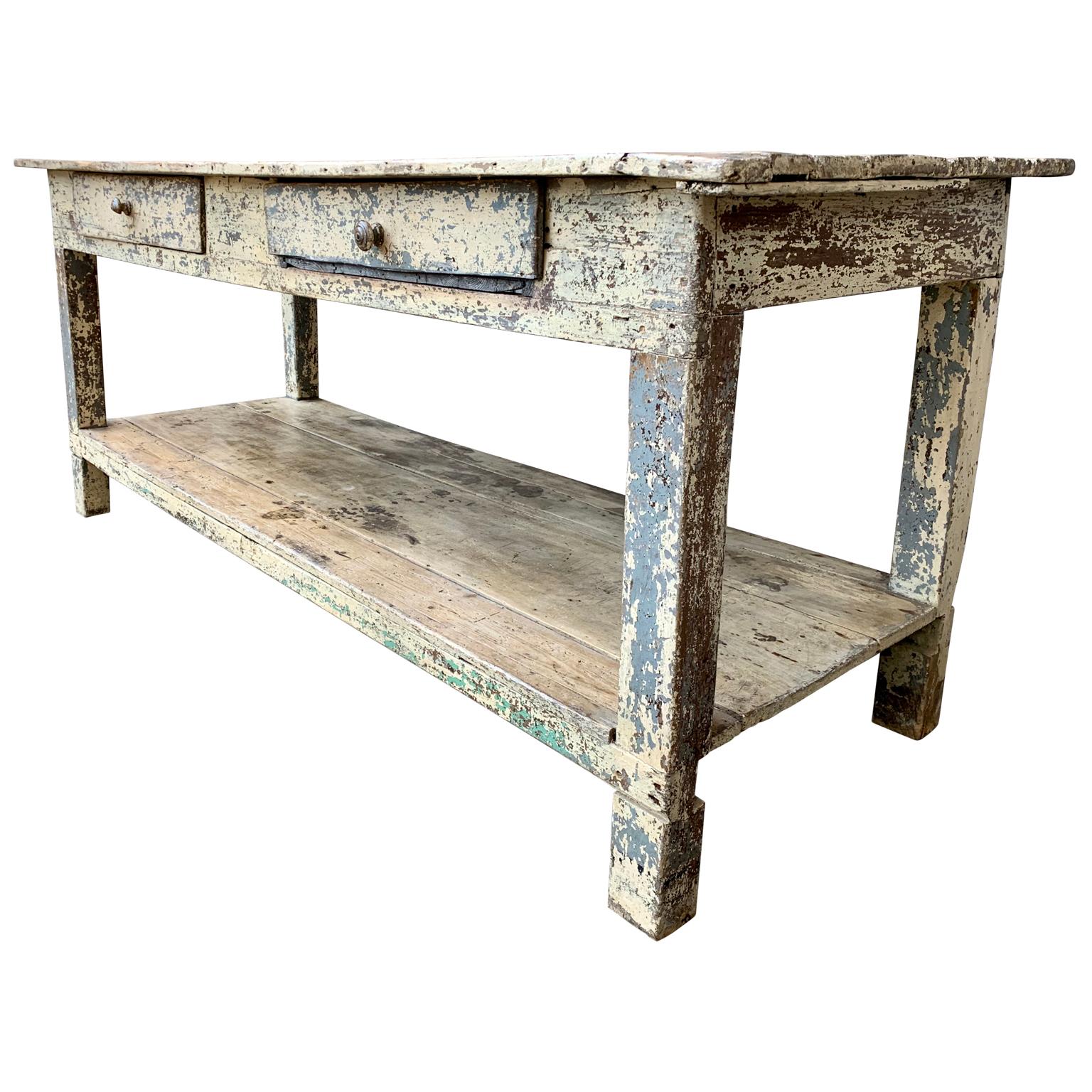 A 19th century painted table from a fabric and upholstery store with 2 large drawers. With all its original rustic patina and different layers of paint that this heavily used farm table has gone through the years. 

 