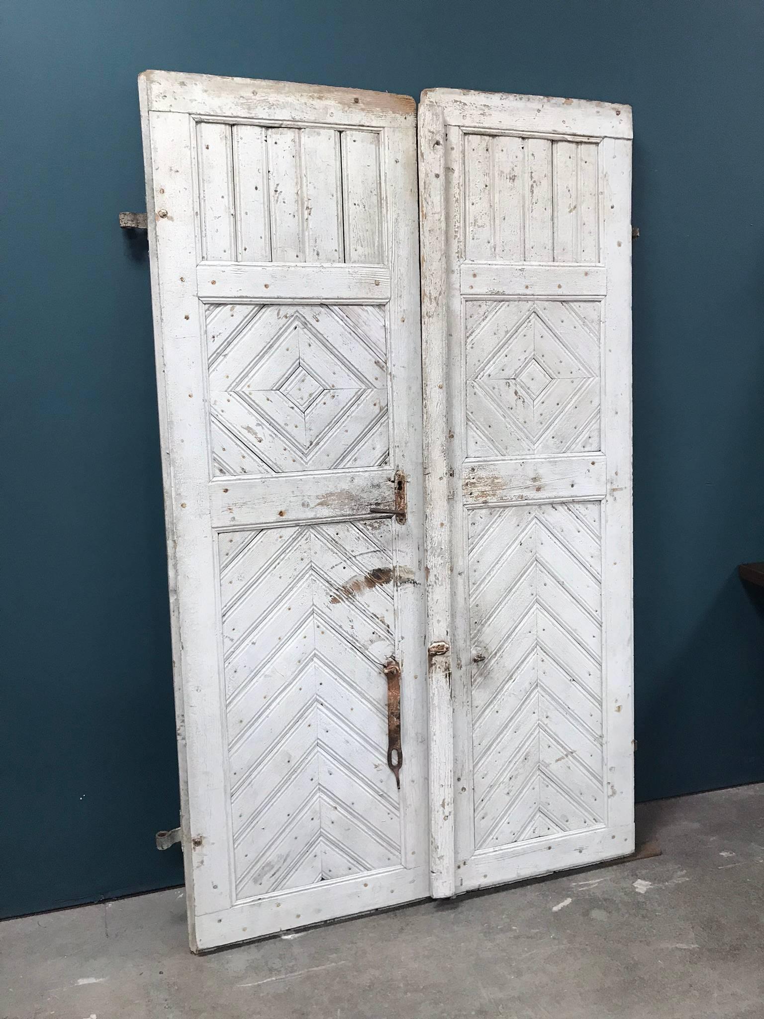 Late 19th century painted French farmhouse doors. The double door features original hardware and a unique chevron and diamond pattern. This piece would make an excellent decorative accent in your home!

Width listed reflects the overall width of