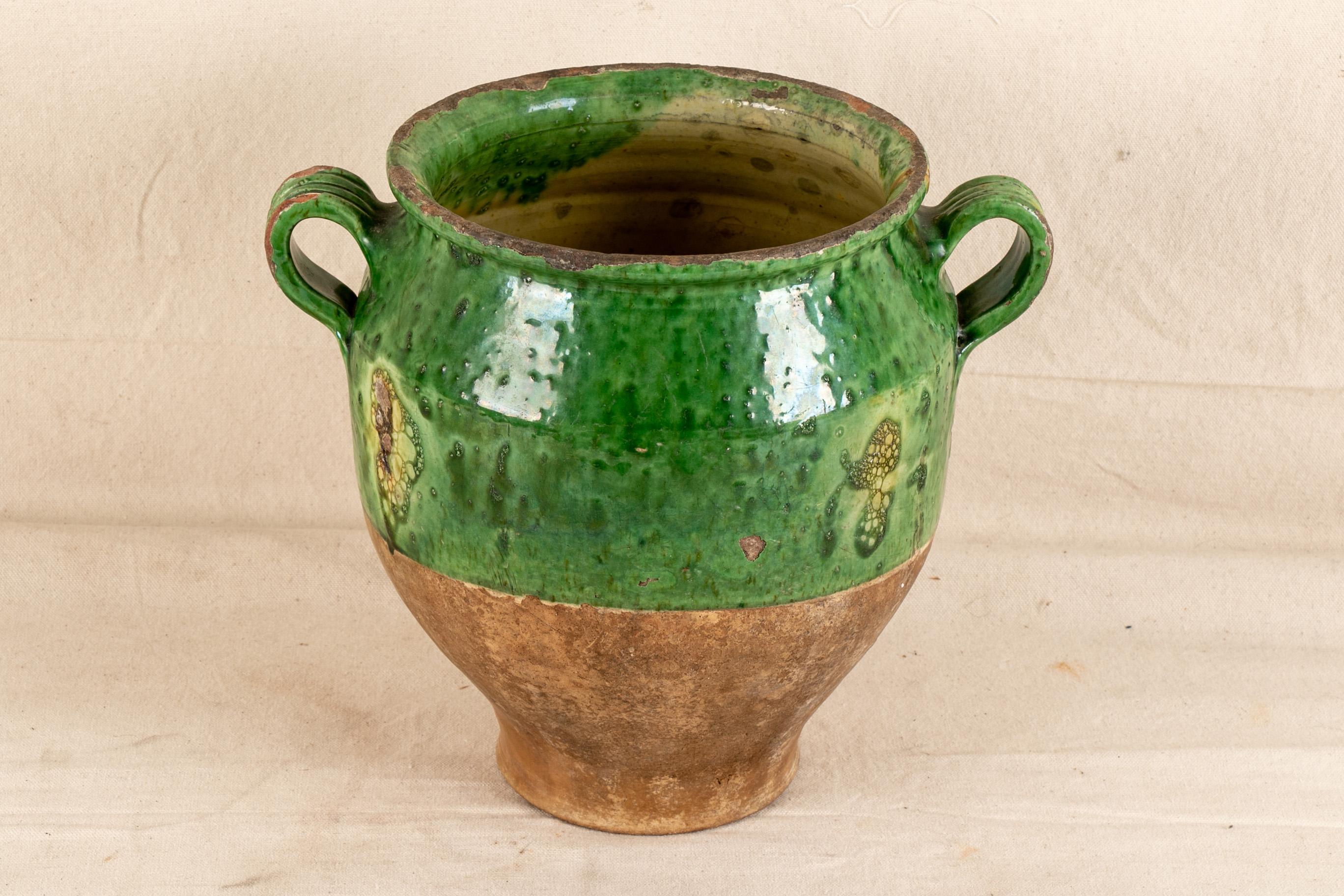 19th century French confit pot, urn form, top half with green glaze and bottom without, flared rim leading to a bulbous top and narrowing toward the base, flanking handles, marked along base 