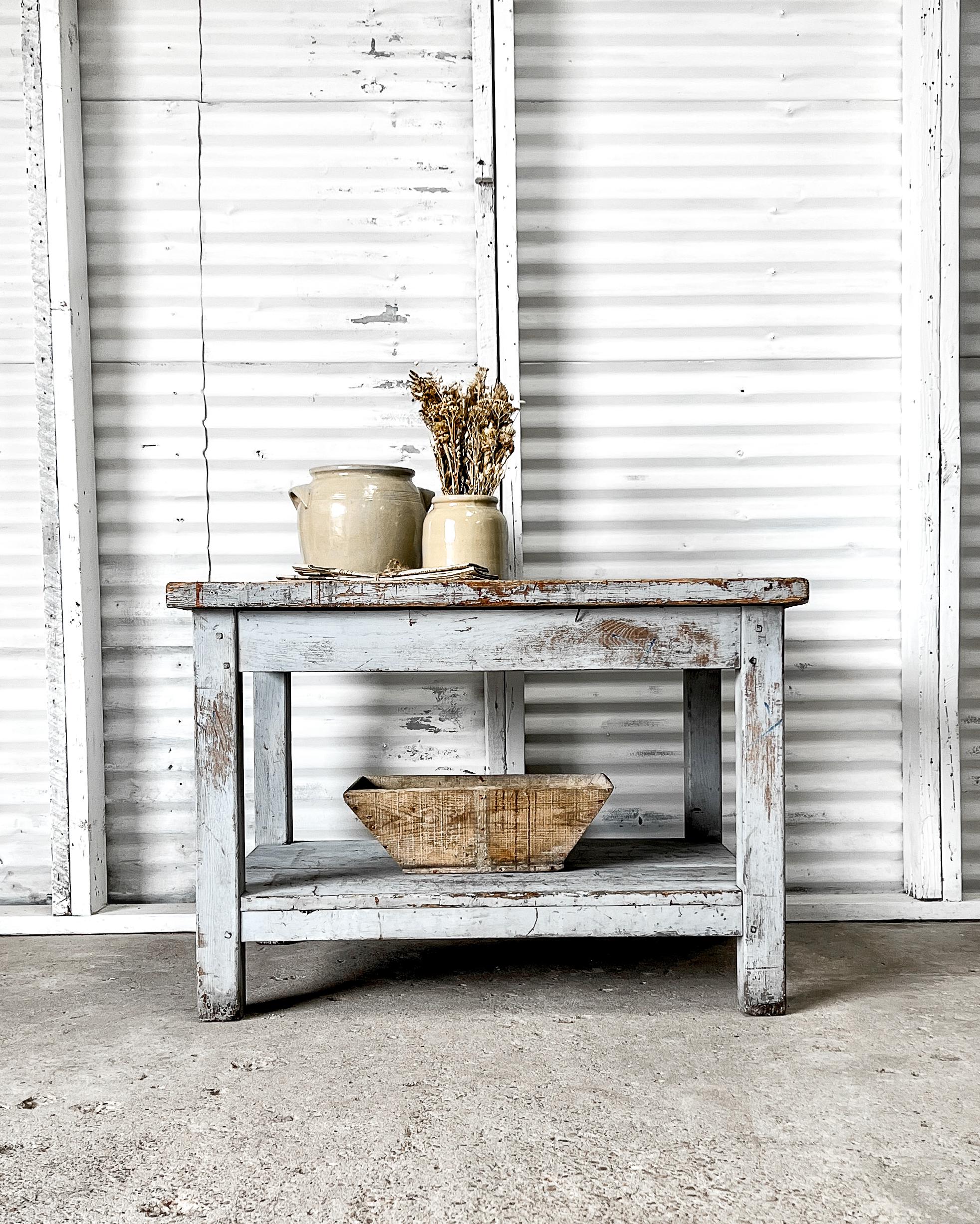 Sturdy and functional, this wonderful old French workshop table features a lovely shade of “French blue” paint on its base and chunky squared legs. The raw, natural wood-planked top is weathered with a great patina. With its straightforward clean