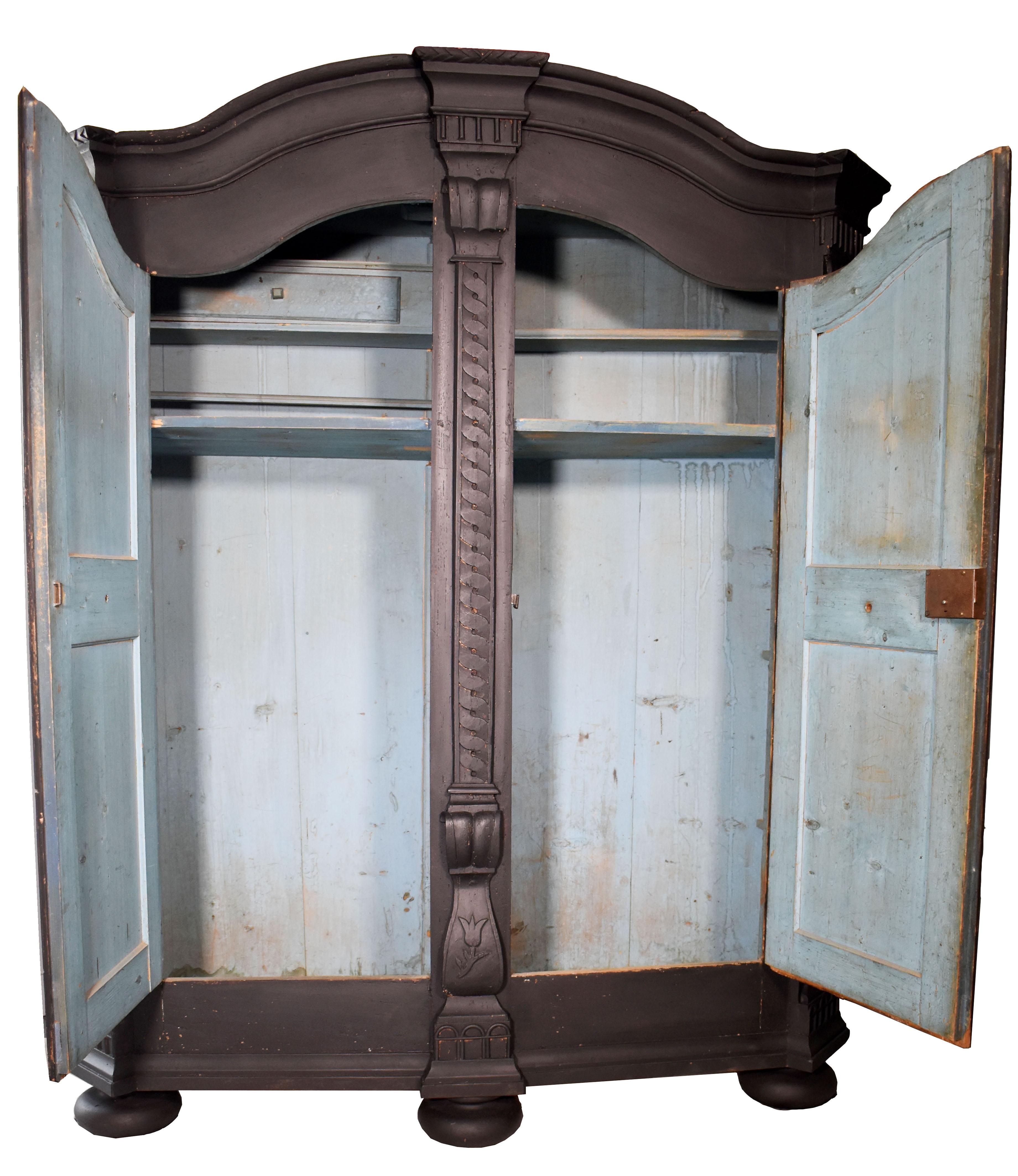 This beautiful 19th-century armoire has a black painted finish, charming bun feet, and expertly carved details. This monumental piece will be an elegant addition to any traditional or eclectic-styled home. Excellent for storage, armoires can be used