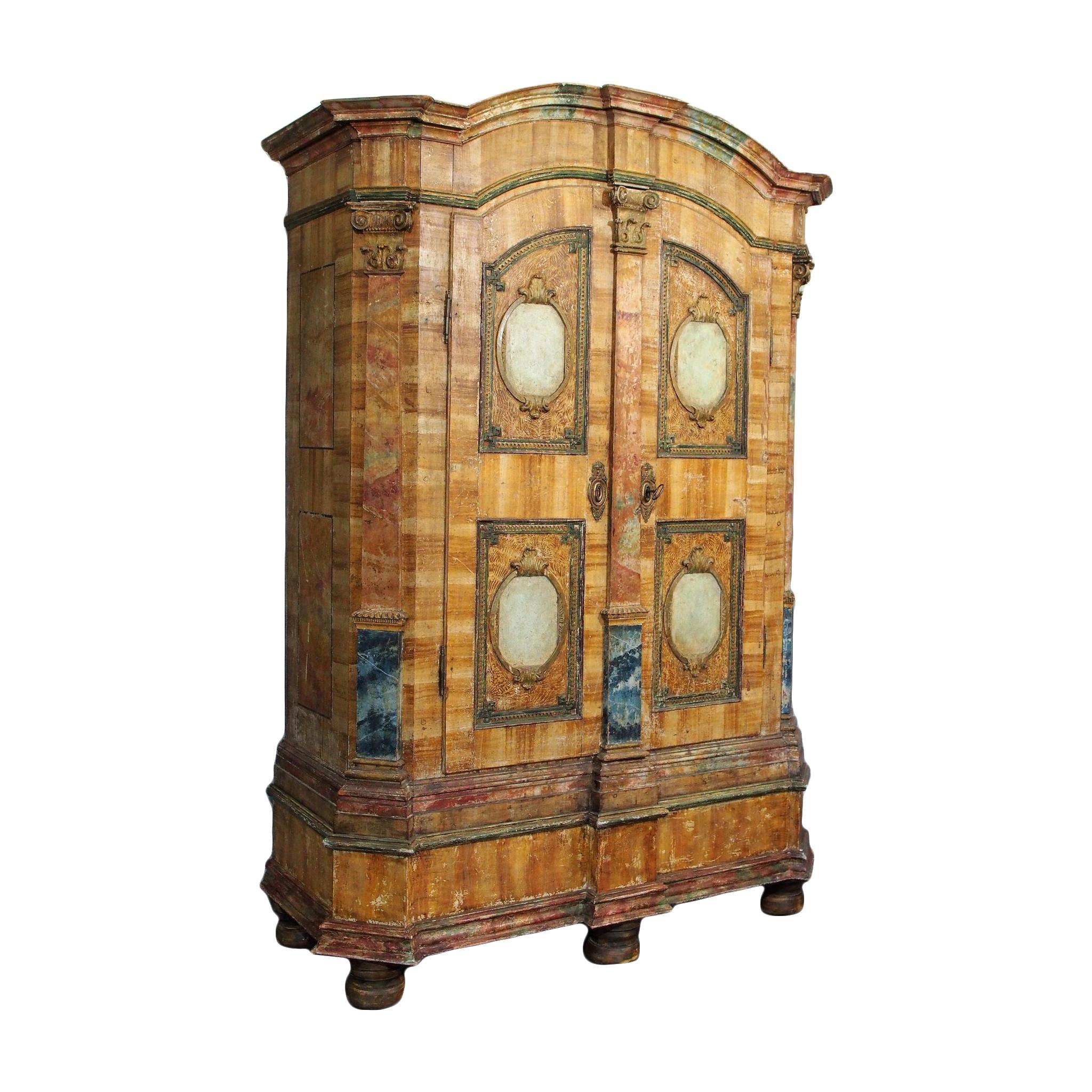 This beautiful 19th century armoire has gorgeous hand painted faux marble accents on double doors, charming bun feet and expertly painted details. A unique polychrome Italian armoire with two doors and stunning patina, this monumental 