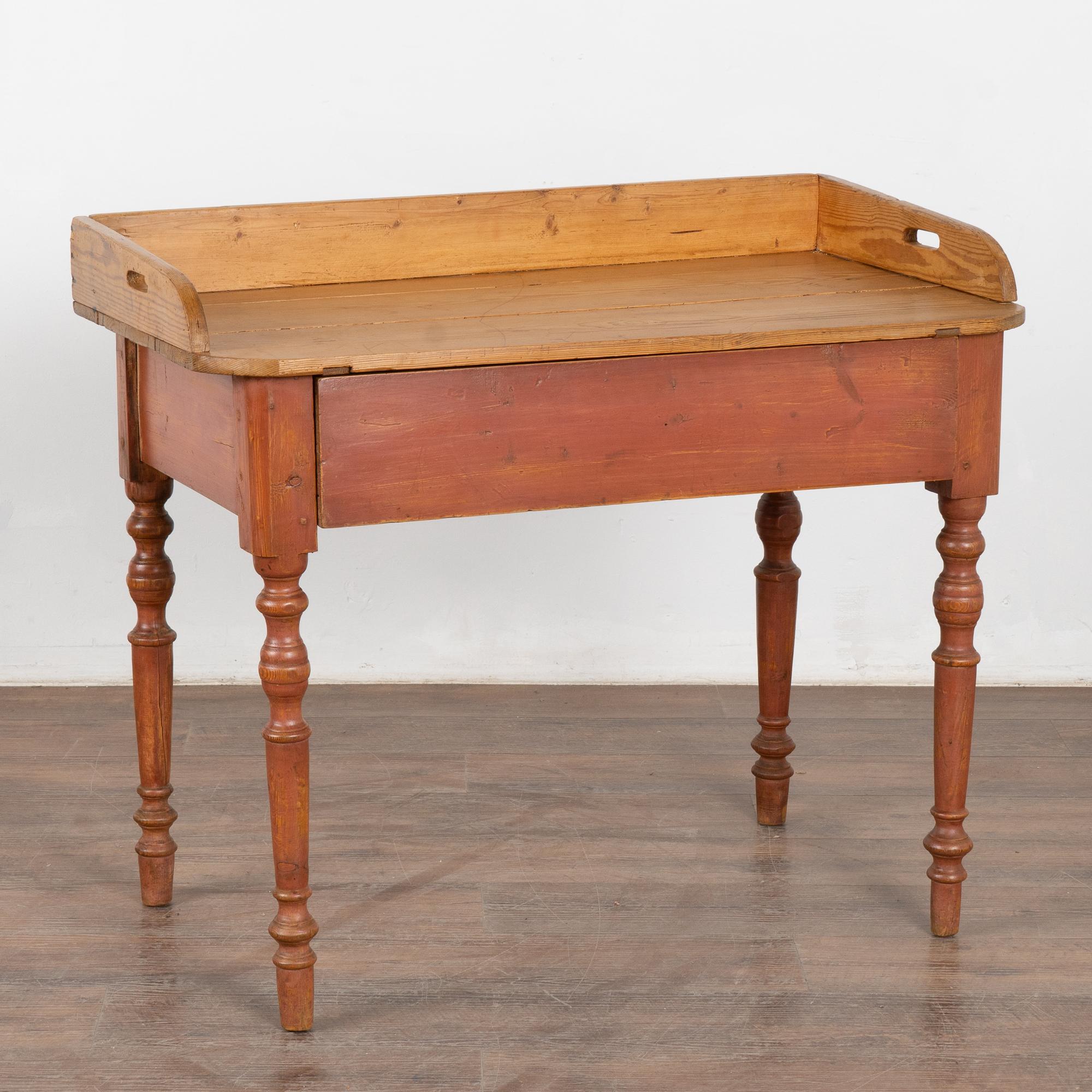 Table d'appoint originale en pin peint de style suédois avec pieds tournés et un seul grand tiroir. 
La base conserve sa finition originale peinte en rouge brique. La partie supérieure a été laissée en pin naturel et est entourée d'un rebord