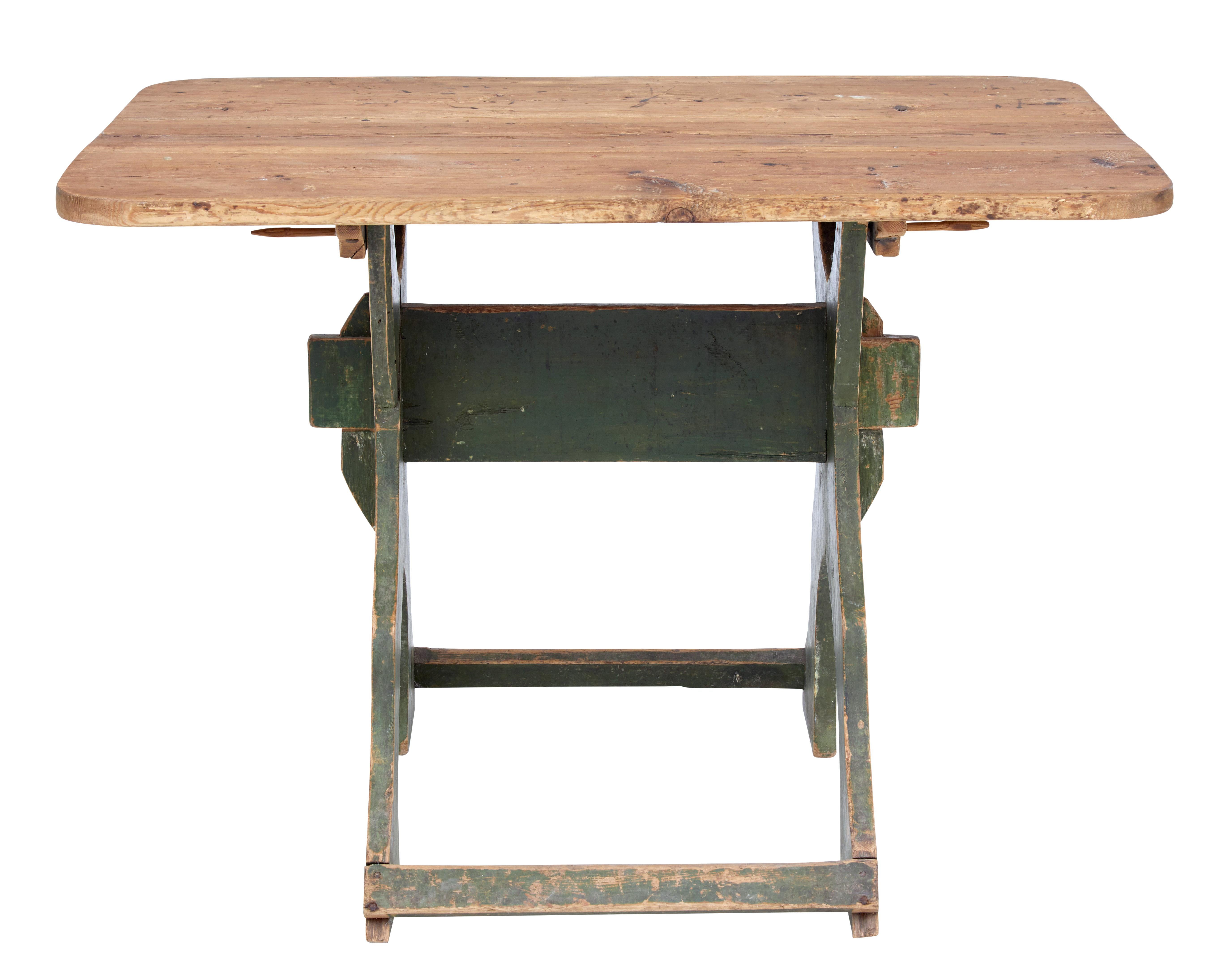 Unusual rustic Swedish pine table, circa 1880.

3 plank removable top with rounded corners. Stands on a shaped x frame base with original paint, held in place by stretcher and pegs.

Ideal for use as a side, centre or small kitchen