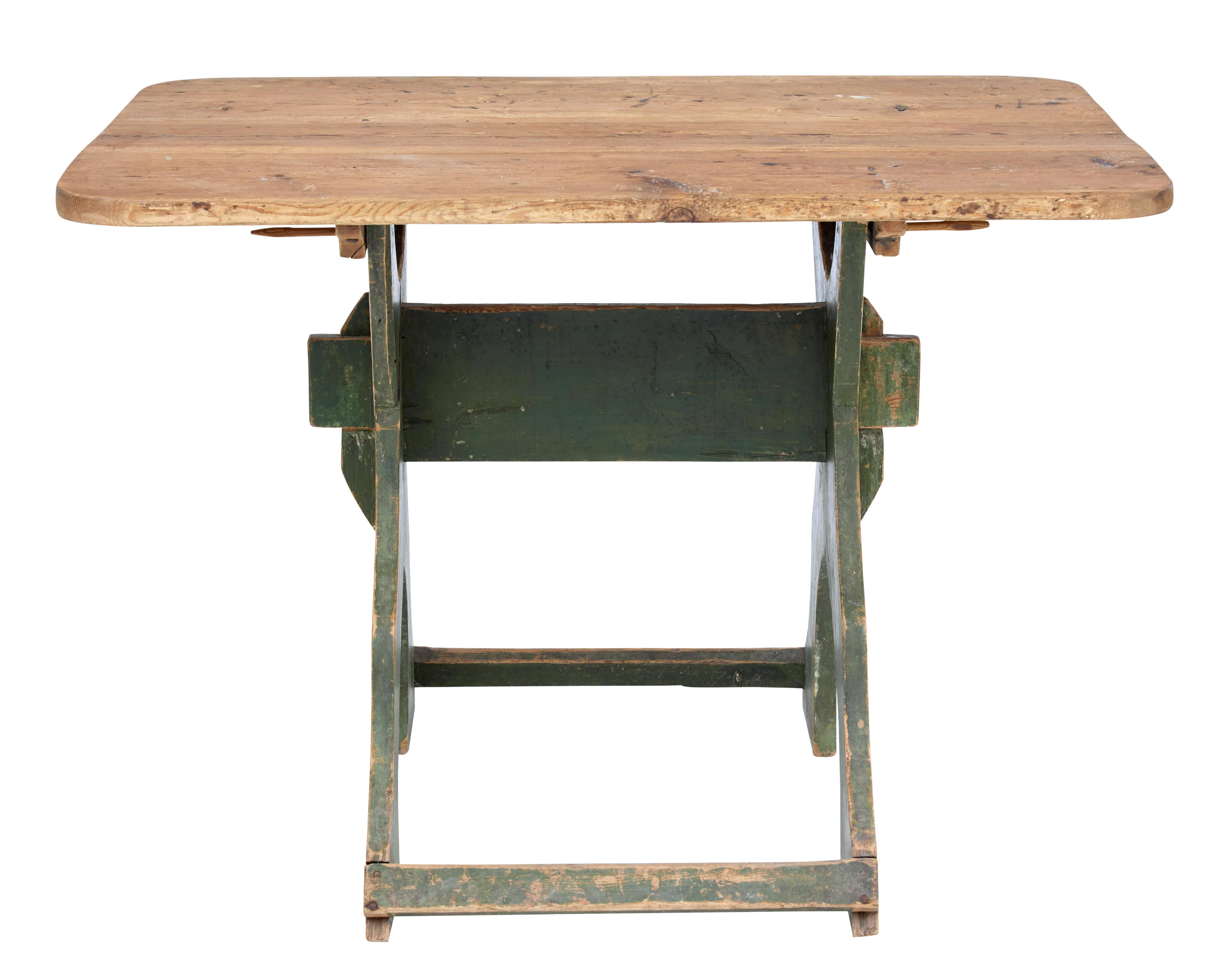Unusual rustic Swedish pine table, circa 1880.

3 plank removable top with rounded corners. Stands on a shaped X-frame base with original paint, held in place by stretcher and pegs.

Ideal for use as a side, centre or small kitchen