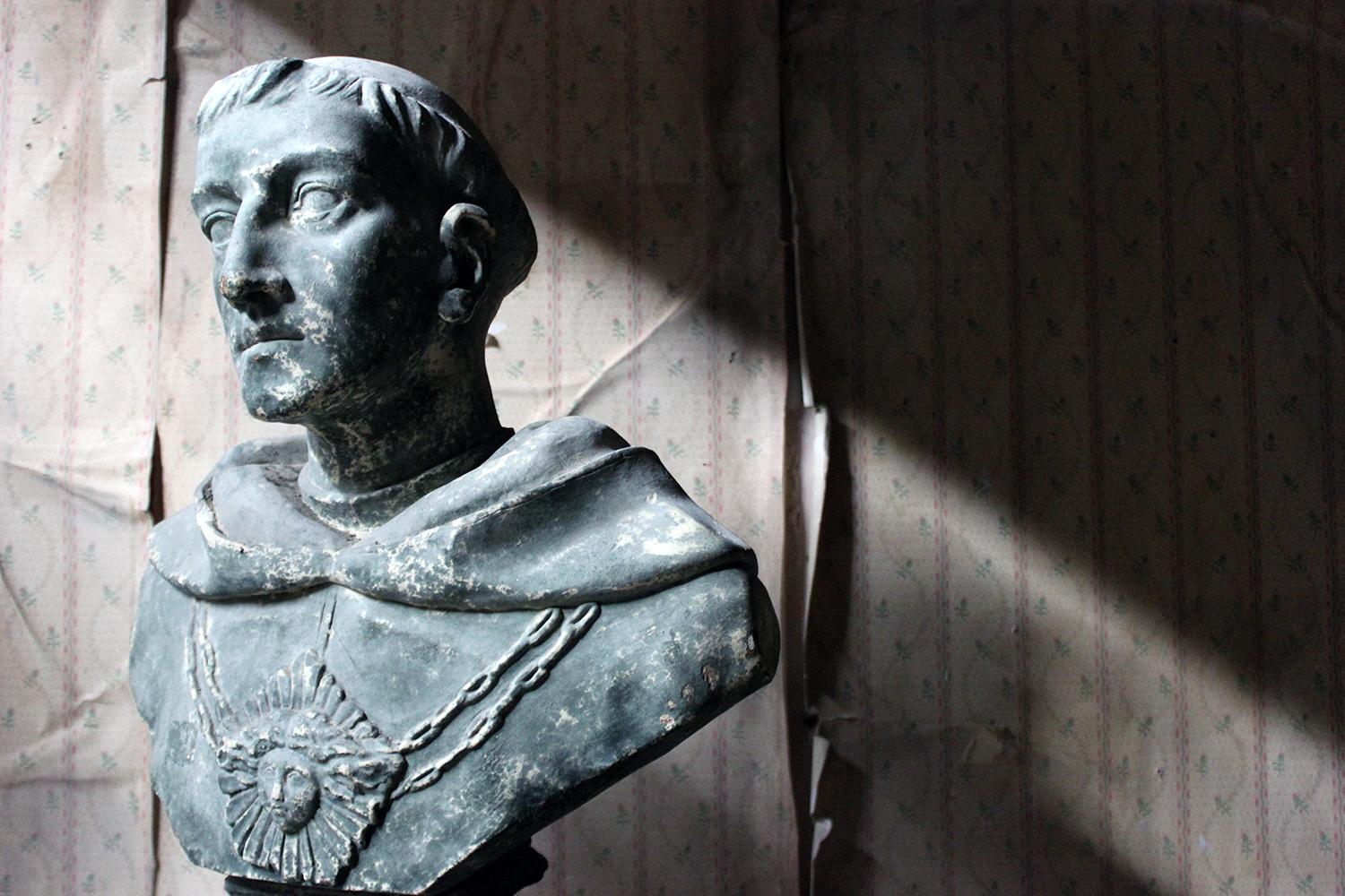The large late Victorian plaster library bust depicting St. Francis of Assisi, wearing ceremonial robes and large pendant on a linked chain, the whole on a stepped socle square base, showing the original laurel green paint now beautifully worn with