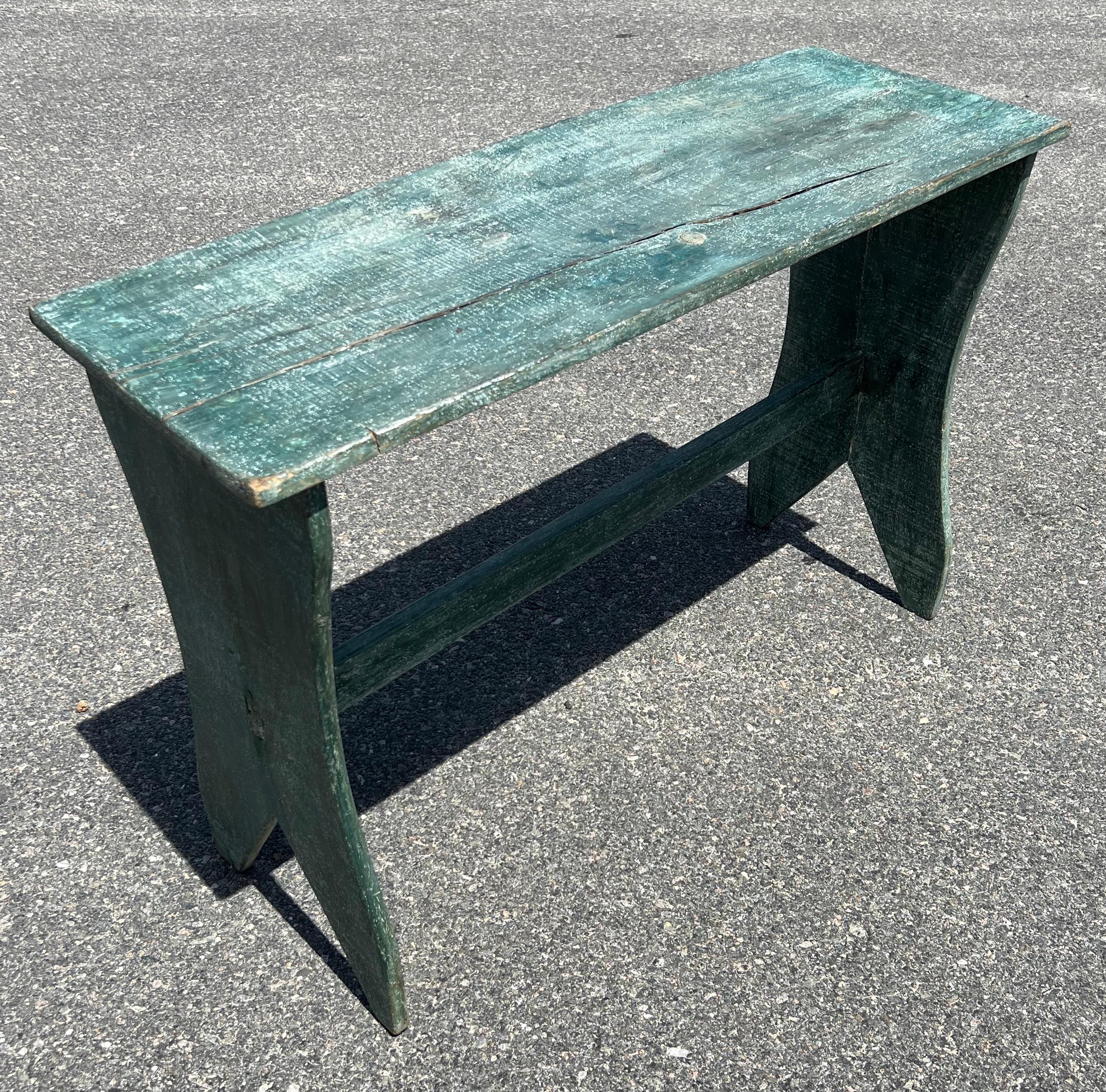 19th century pine side table(or tall bench) in blue-green paint with stretcher and boot jack base. Old crack in top.