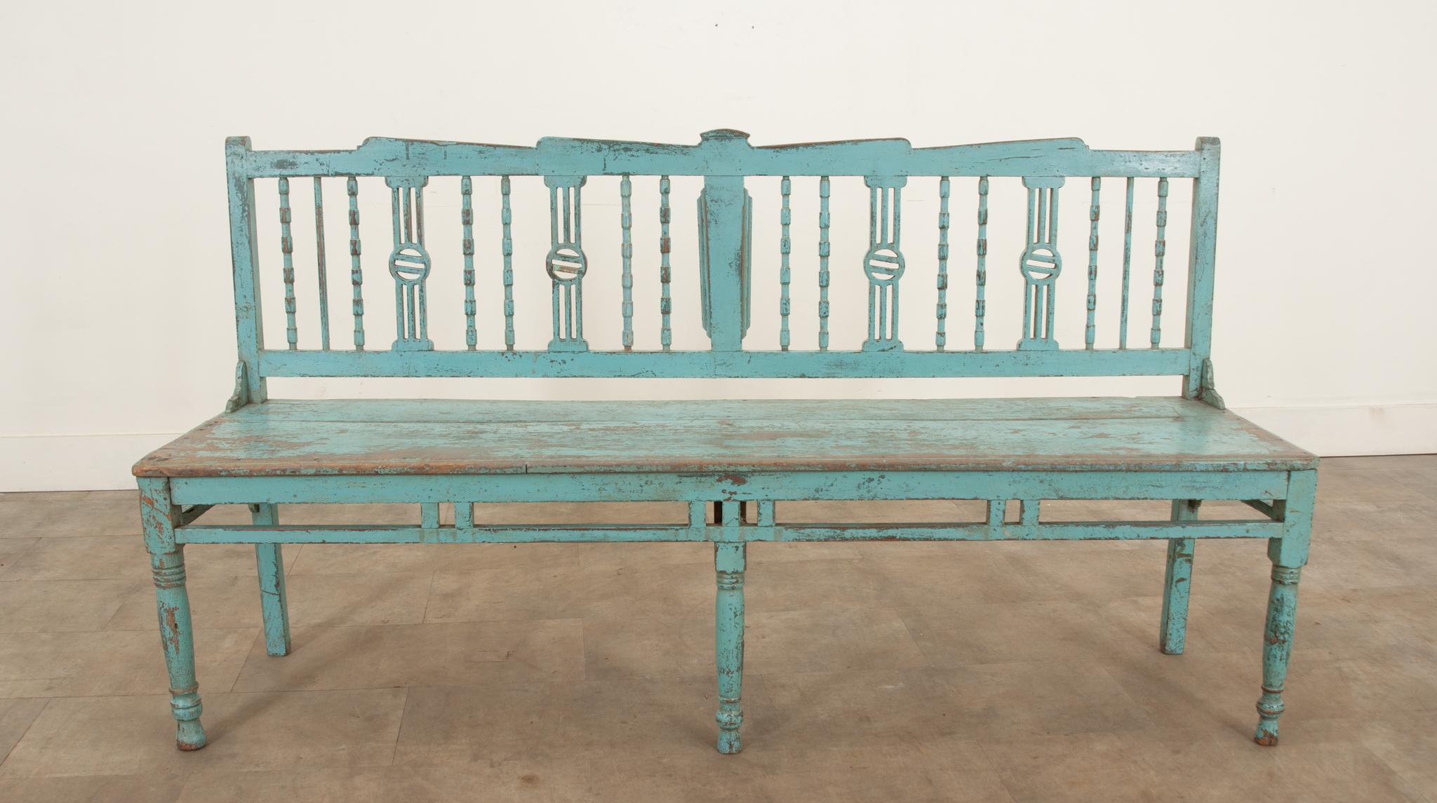 A European late 19th century painted bench circa 1890. This bench is an eye-catcher of good quality with pleasing and well patinated blue paint and an attractive shaped backrest with beautifully carved decorative spindle supports, and it stands on