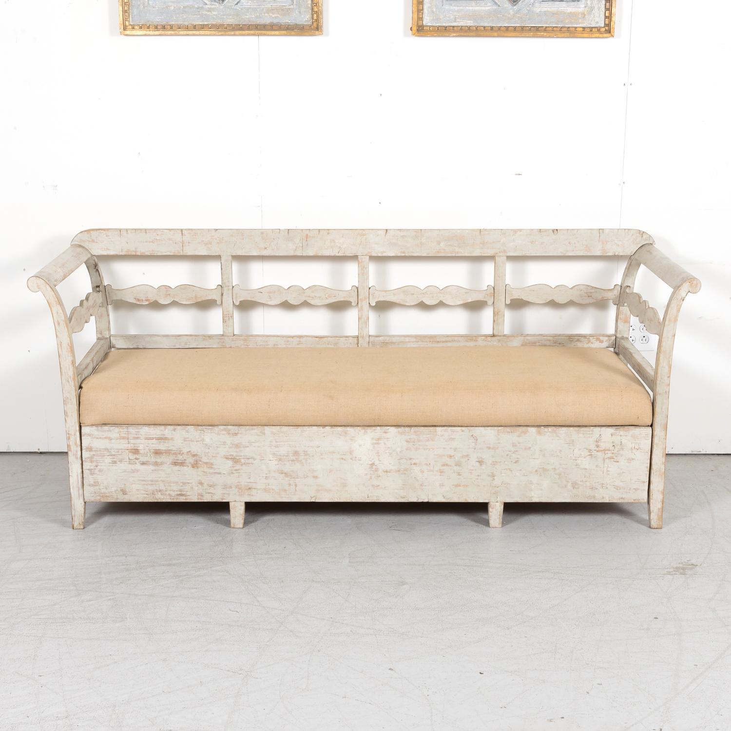 A 19th century painted Swedish hall or kitchen bench with drawer concealing a trundle bed, circa 1870s. Classic with graceful curved lines, this beautiful bench comes with a seat cushion and the drawer can be used for storage if needed.

For