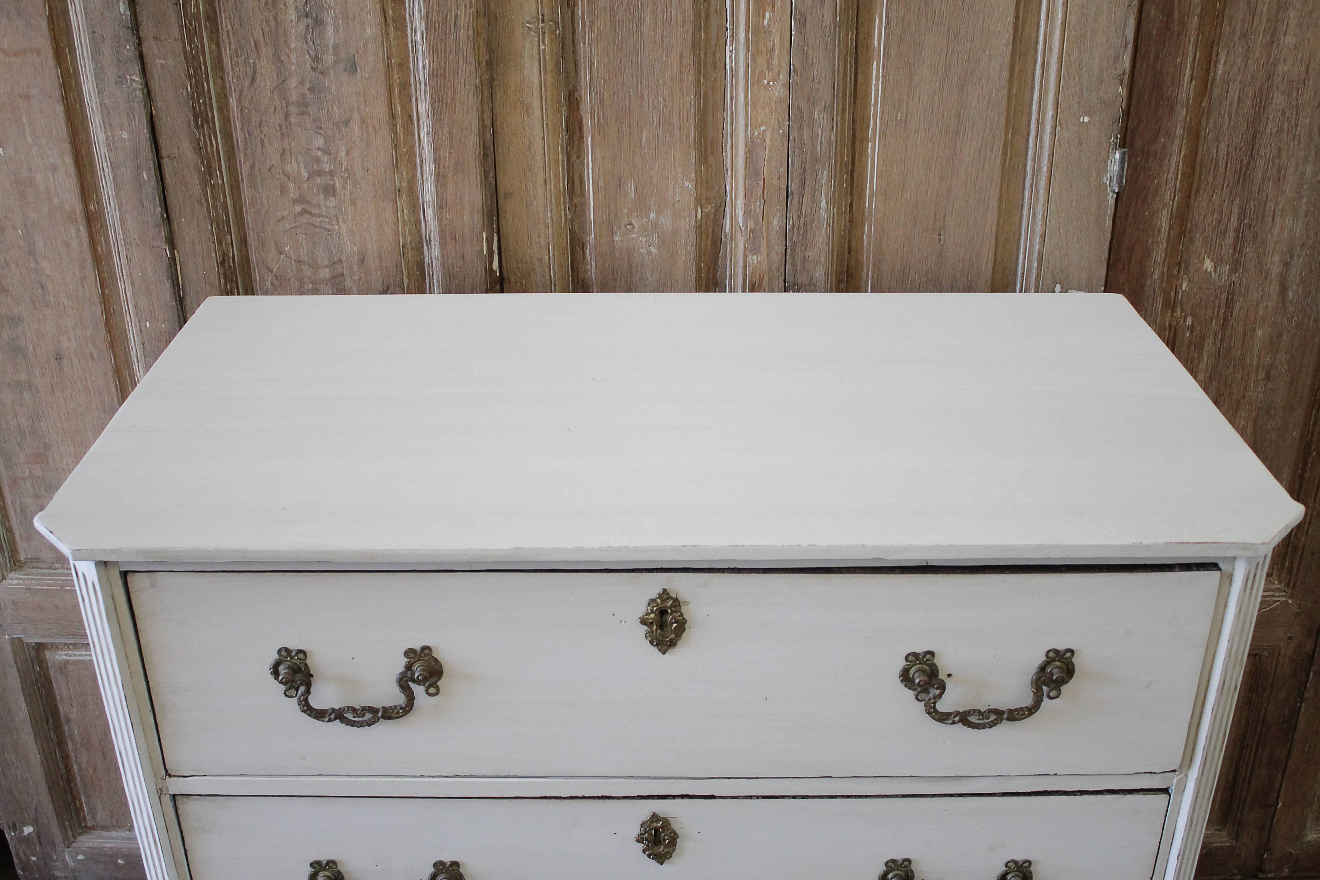 19th century painted Swedish style three-drawer commode
Painted in a pale oyster white finish, with distressed edges, and antique hand glazed patina. Color lends to a soft French grey. Original hardware, drawers open and close with ease. Solid