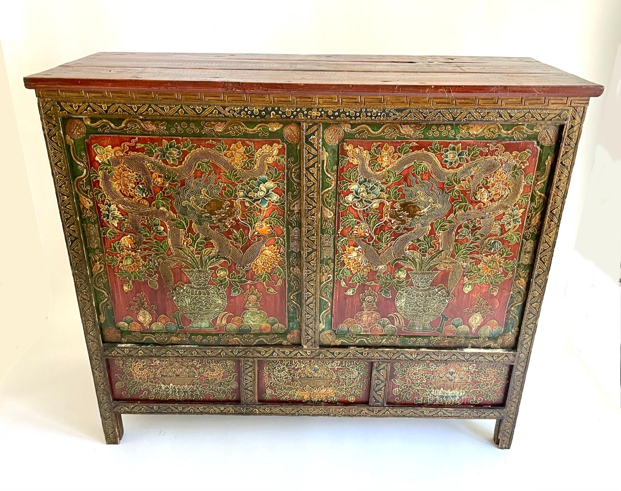 This 2 panel cabinet is beautifully painted with a pair of dragons, vases and lotus blossoms adoring both the front doors. Both sides of the cabinet are painted with the same floral details as the front. The cabinet is hand carved and painted in the