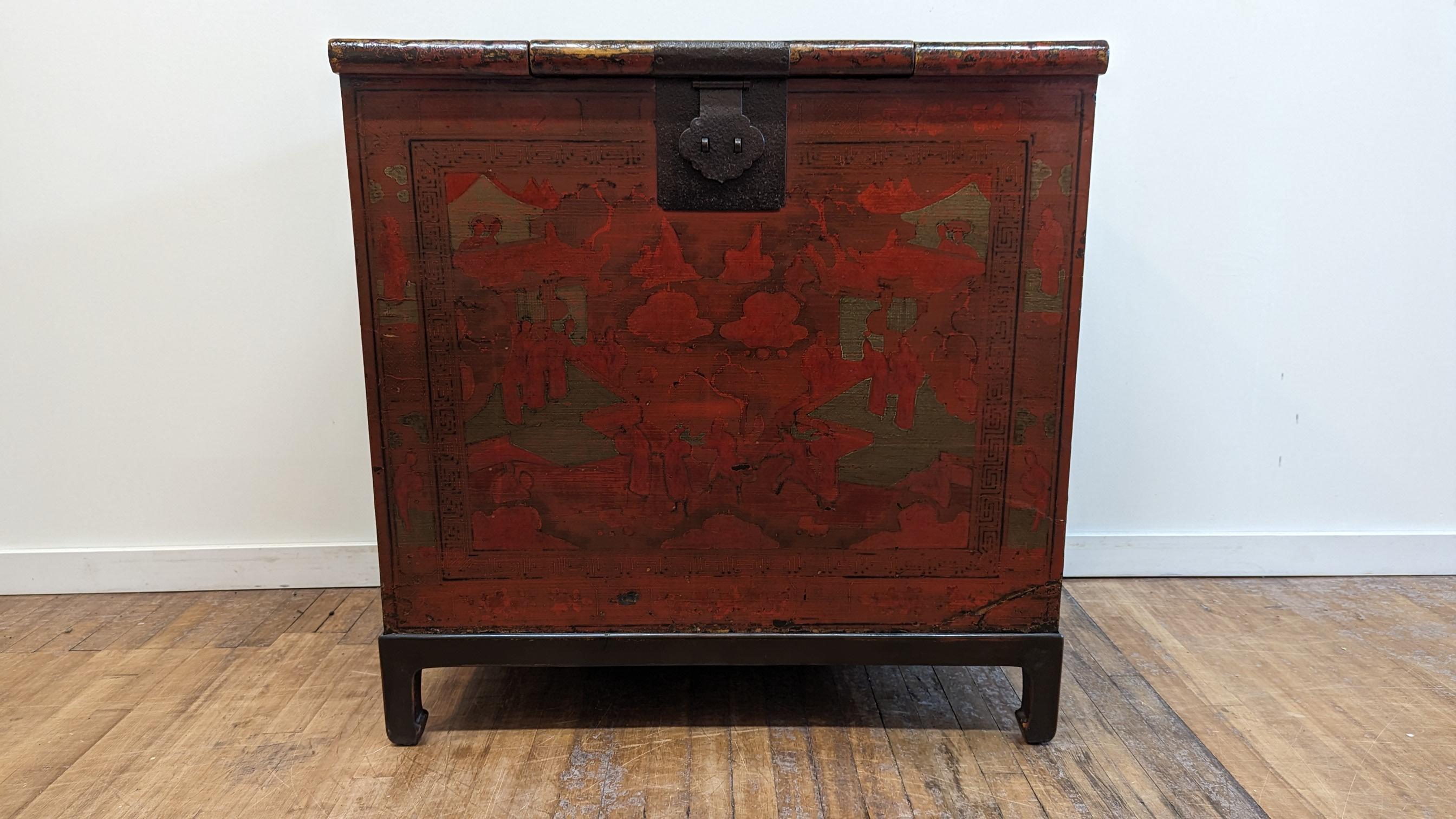 19th Century Lacquered Chinese Trunk of the Qing Dynasty.   Large wardrobe chest with worn red lacquer and hand gilt painting.  Unlike most Traditional Trunks a very large lip - rim overhangs the top front of the Chest.  A smaller opening to the top