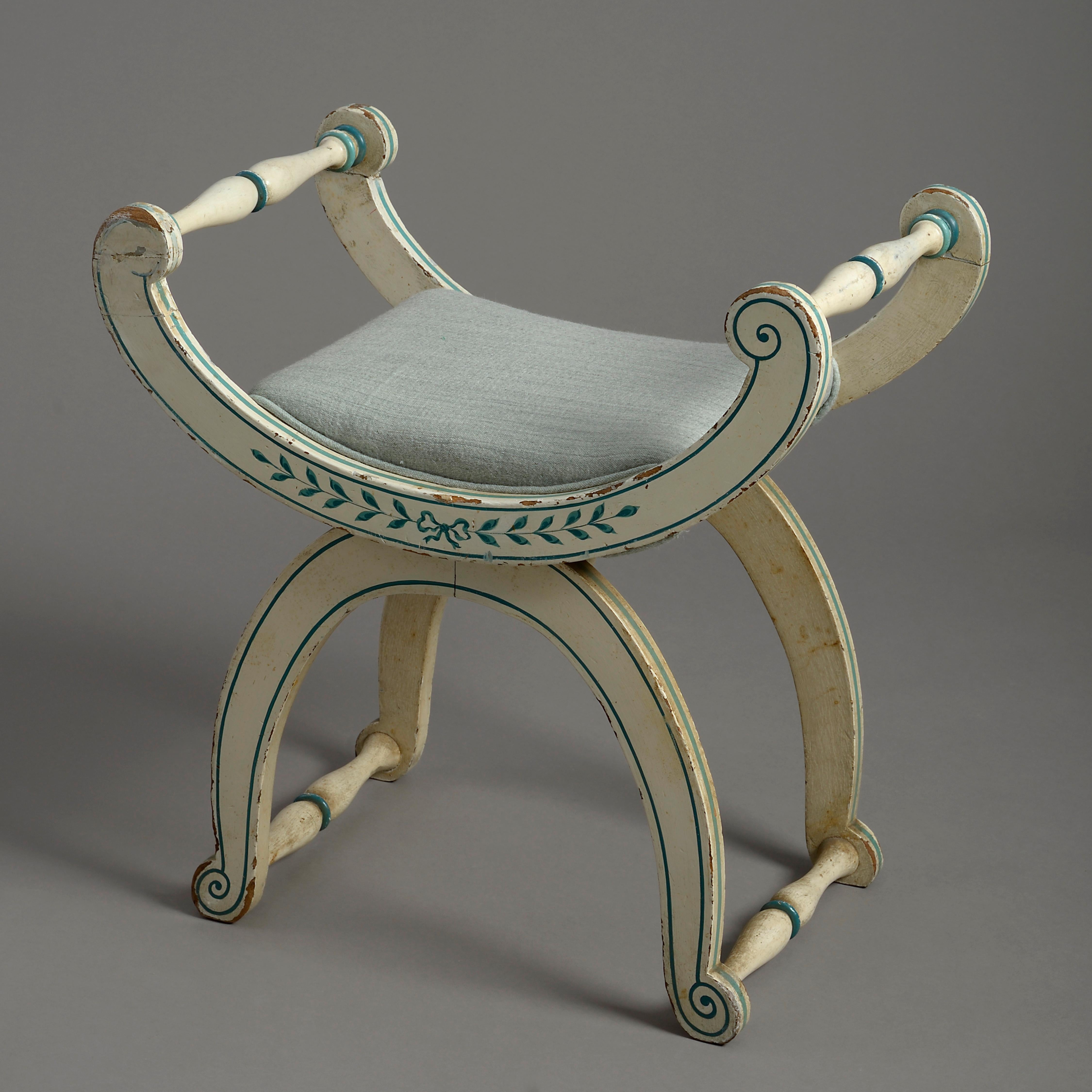 A mid-19th century cream blue painted x-frame stool, the scrolling frame with spindle supports with an upholstered seat.