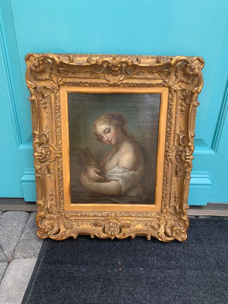19th century painting of woman holding rabbit in giltwood frame.