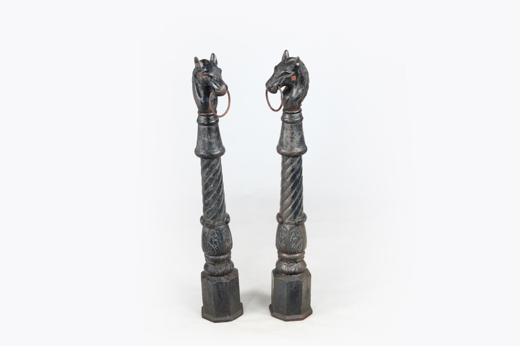 Pair of heavy 19th Century hitching posts with distinctive horse heads and movable horse bits on garlanded pillars atop moulded octagonal plinth bases. The black painted cast iron has an aged patina and the elegant form of both posts have superb