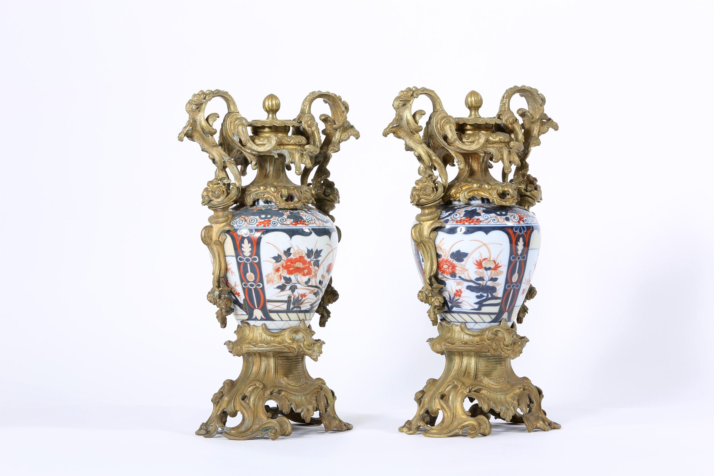 Early 19th century pair of gilt bronze mounted imari porcelain decorative vases or urns. Each urn is in good antique condition with minor wear consistent with age or use. Each urn stand about 20 inches tall x 15 inches wide x 7 inches deep.