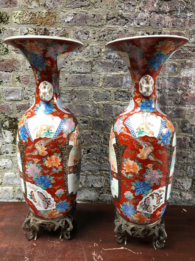 A monumental pair of Japanese Meiji period Imari Porcelain vases, with foliage bronze stands, dating from the late 19th Century.

Each vase features a bulbous shape with the traditional smooth rim, over the body decorated with reserve panels