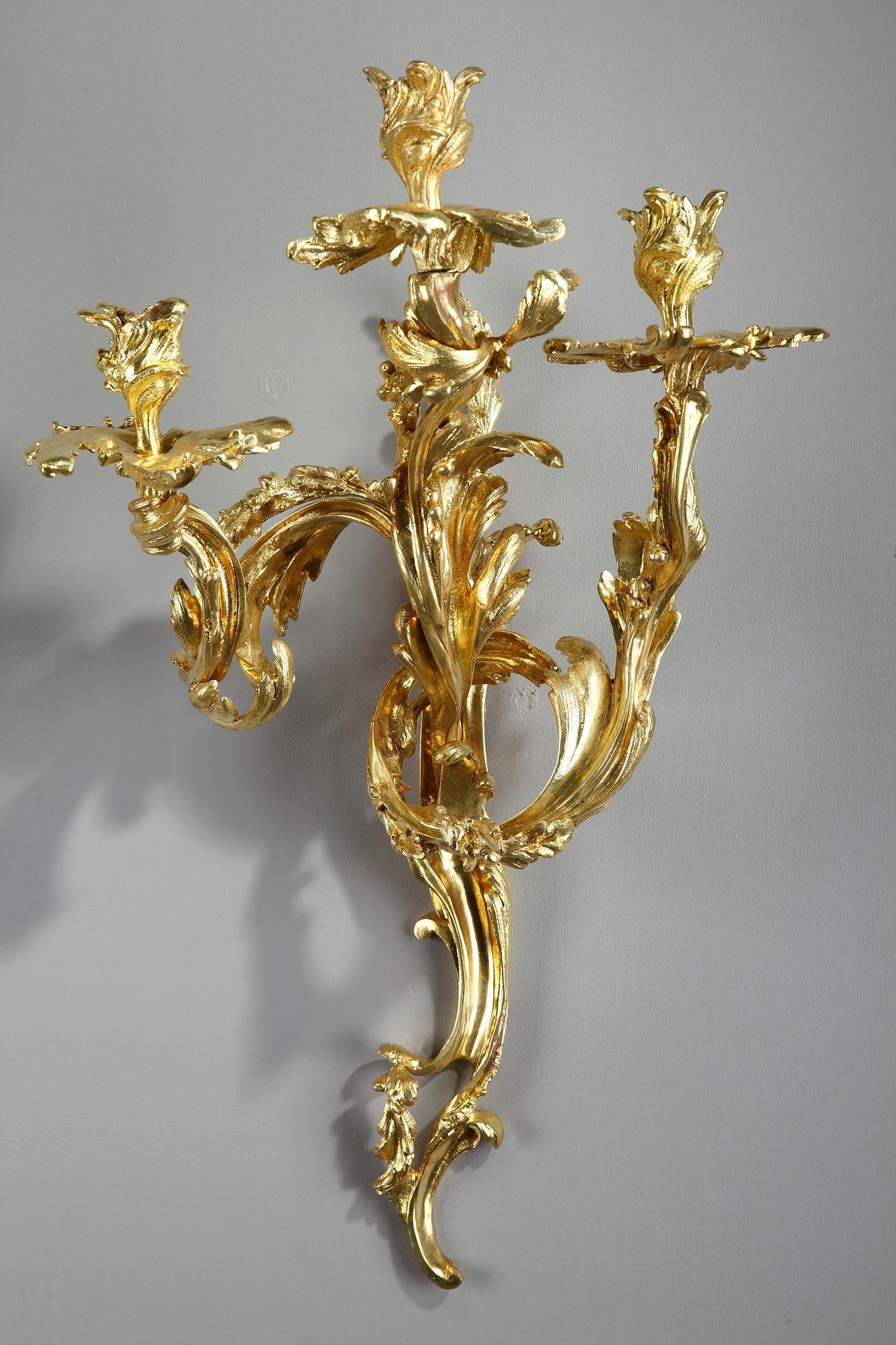 Pair of Napoleon III three-light candle wall sconces crafted in gilt and chiseled bronze. They are richly decorated with flowing and asymmetrical foliage in Louis XV style, largely imitated in the second half of the 19th century.

circa