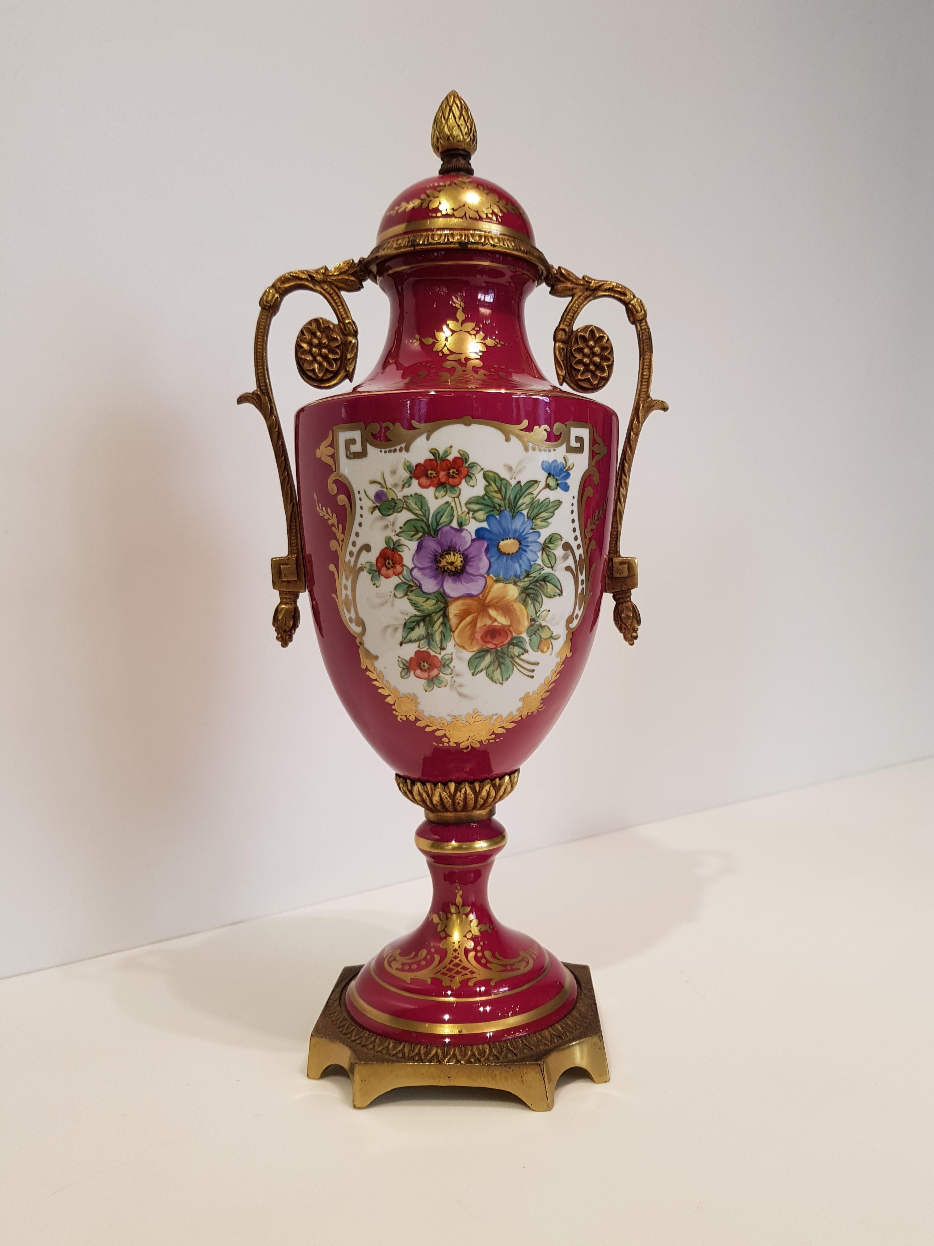 Ancient set of two-handled French ceramic vases crafted and hand decorated in the 19th century.
The vases are characterized by a purpura and gold bottom, with florar polychrome pattern with a fix lid decorated with a pinecone. The base is in golden