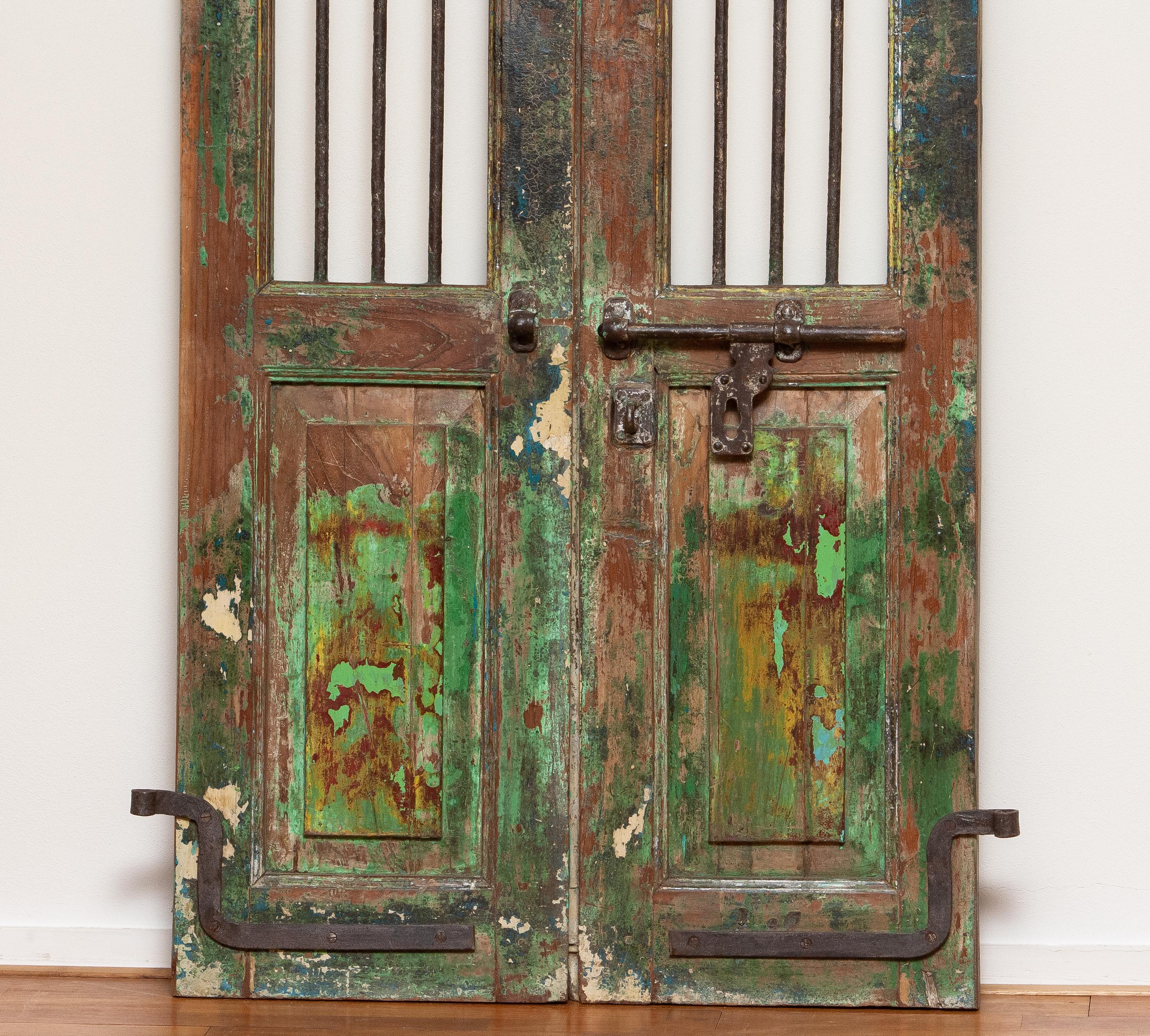 19th century Indian window or door shutters. Complete with original hangings and metal mechanism for locking. The doors have panels and above the lock mechanism each door has three steel bars. 
These doors have a great patina true the years and are