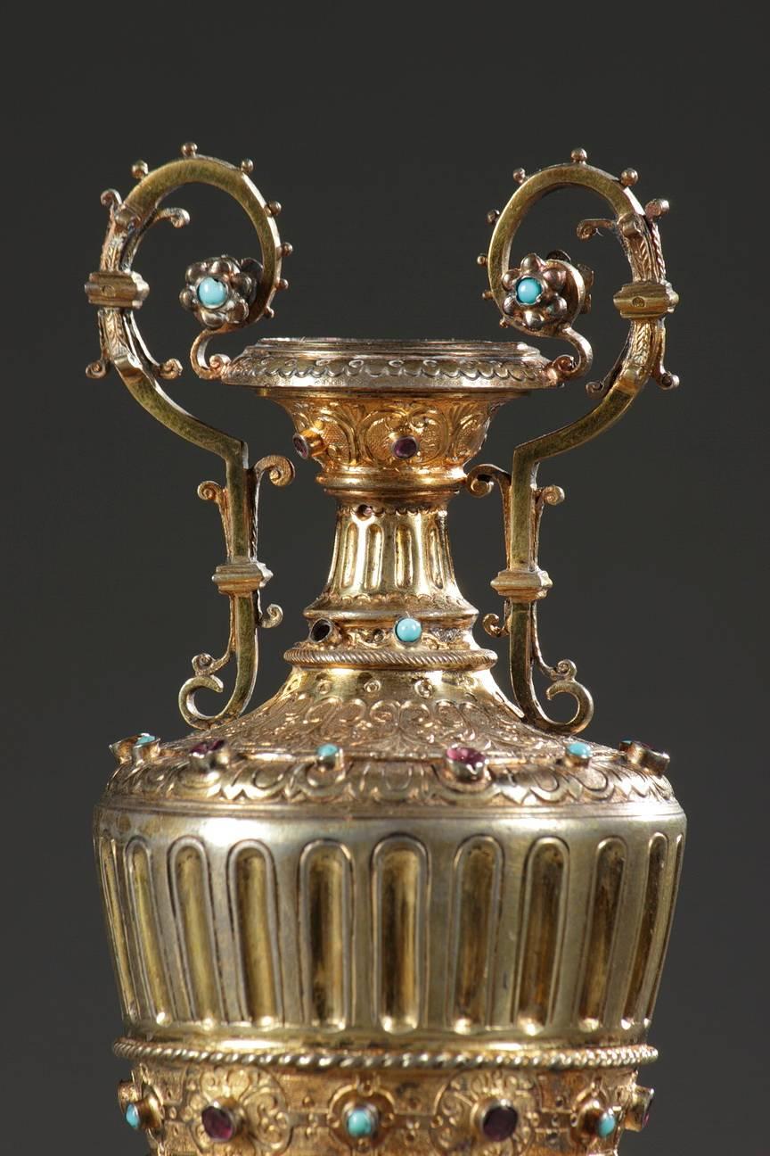 Paire de petits vases de forme étrusque. Artisanat austro-hongrois du XIXe siècle en vermeil et cabochons. Ils sont sculptés de cannelures et de motifs végétaux et ornés de frises de pierres précieuses alternant turquoises et améthystes,

 
vers