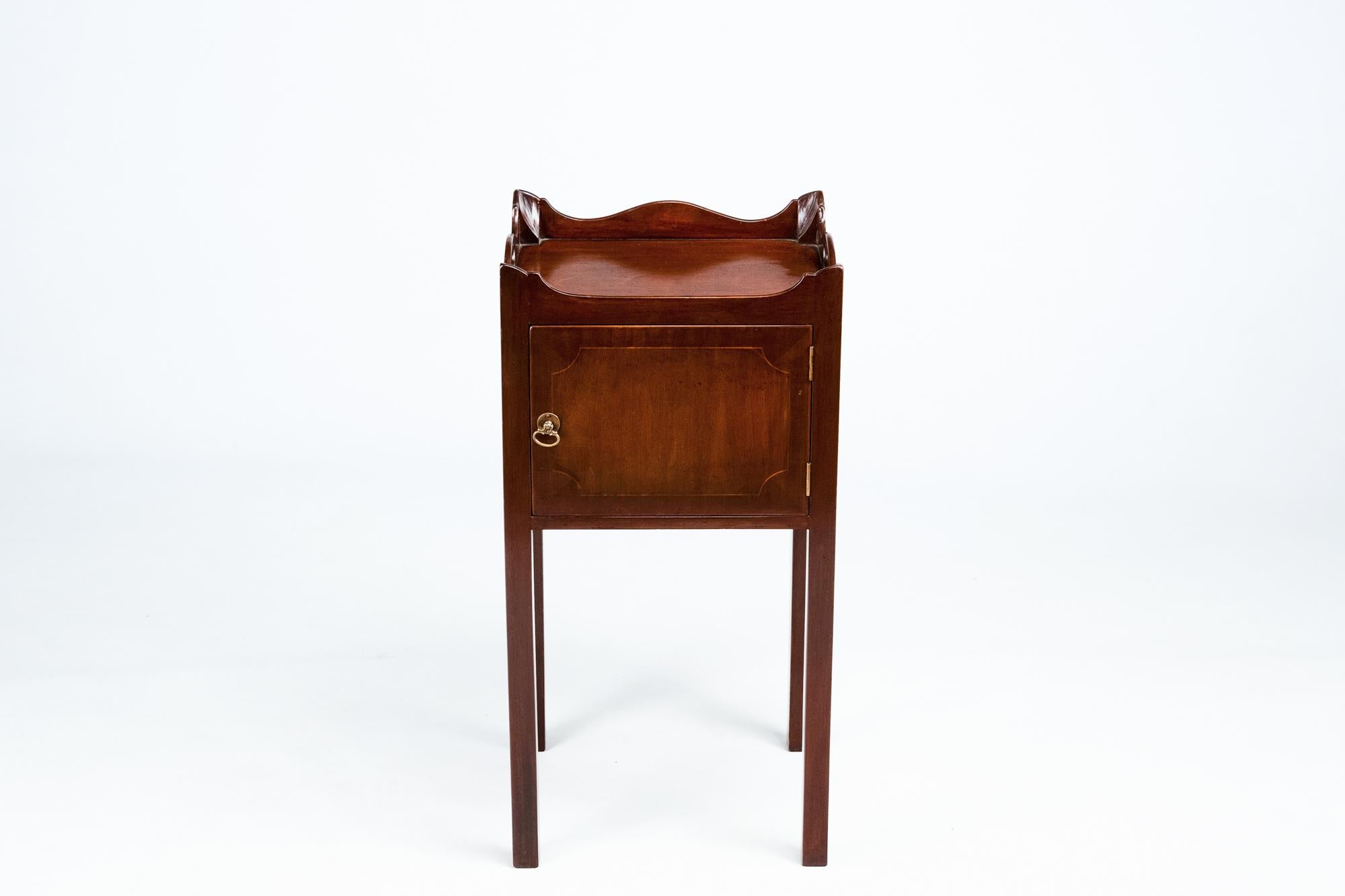 19th century pair of mahogany bedside lockers, the shaped galleried top with pierced handles and canted corners raised over single door with satinwood line inlay and brass pull supported on straight leg.
