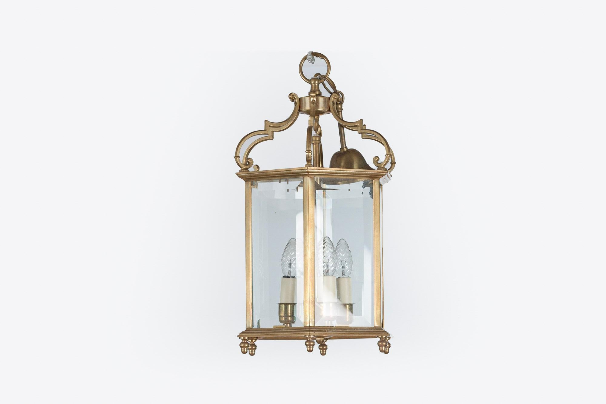 19th century pair of brass hexagonal lanterns, the finial base supporting the beveled glass case enclosing three branch light fitting surmounted with scroll detail, electrified.