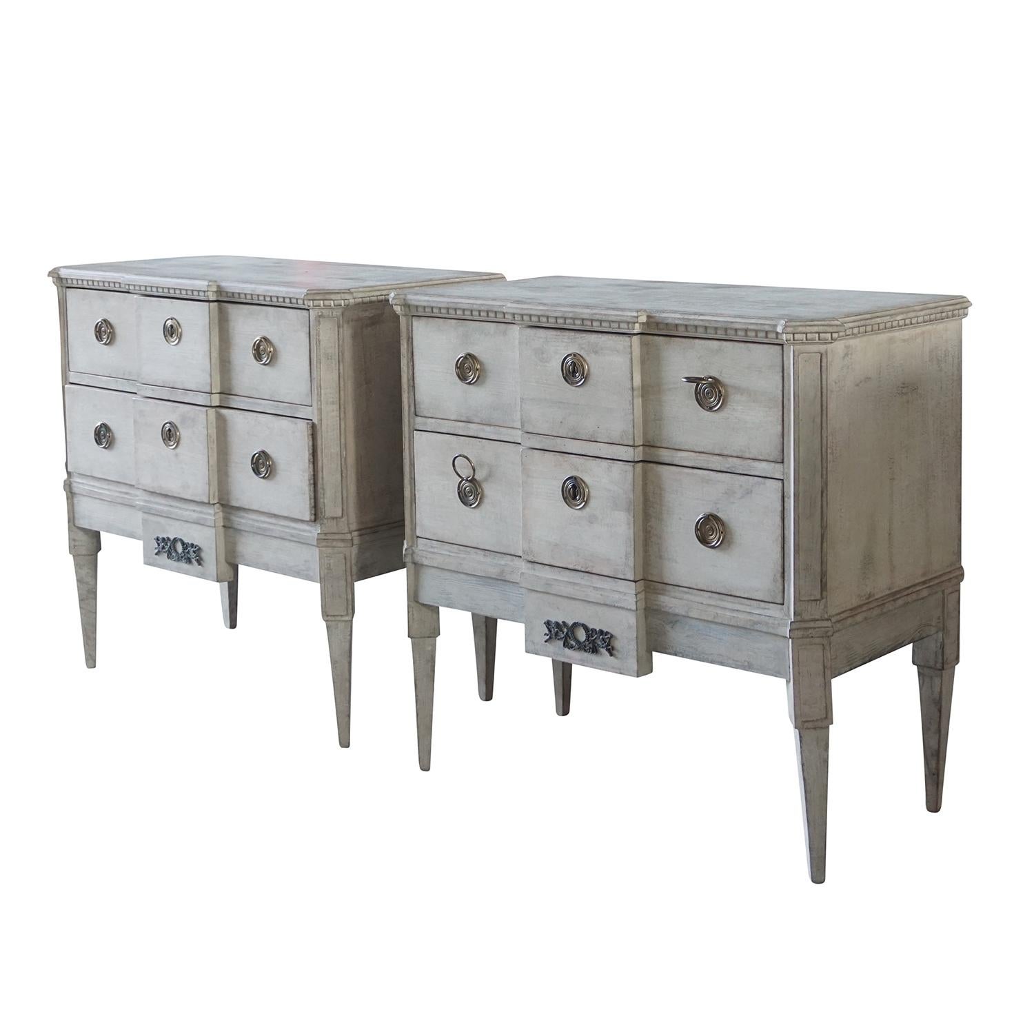An antique pair of neoclassical commodes with two drawers and key, of light grey painted pinewood. The Swedish Gustavian hand carved chests are in good condition, detailed in the neoclassical Greek style with their original chrome hardware and keys.